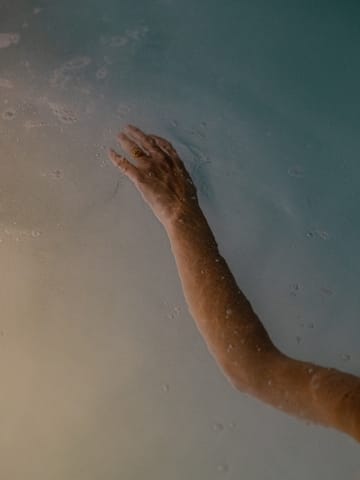 a person's hand reaching out to the water