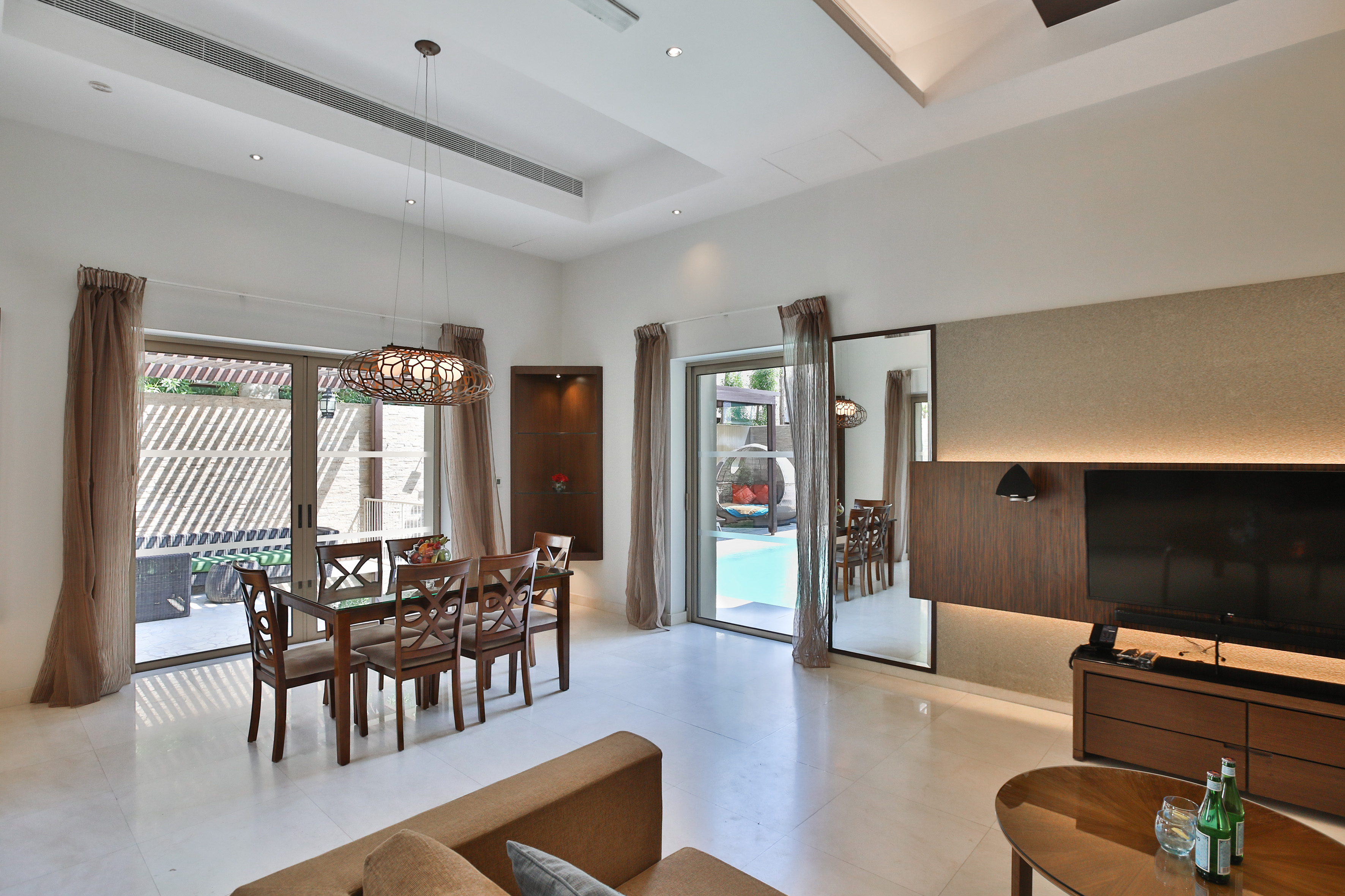 Modern open-plan living and dining room with pool view.