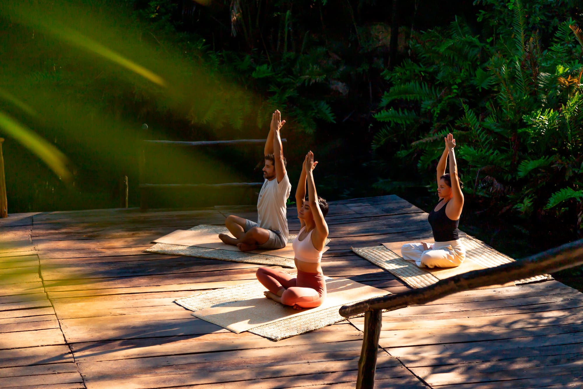 a group of people sitting on mats with their hands up