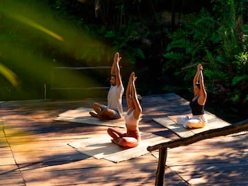 a group of people sitting on mats with their hands up