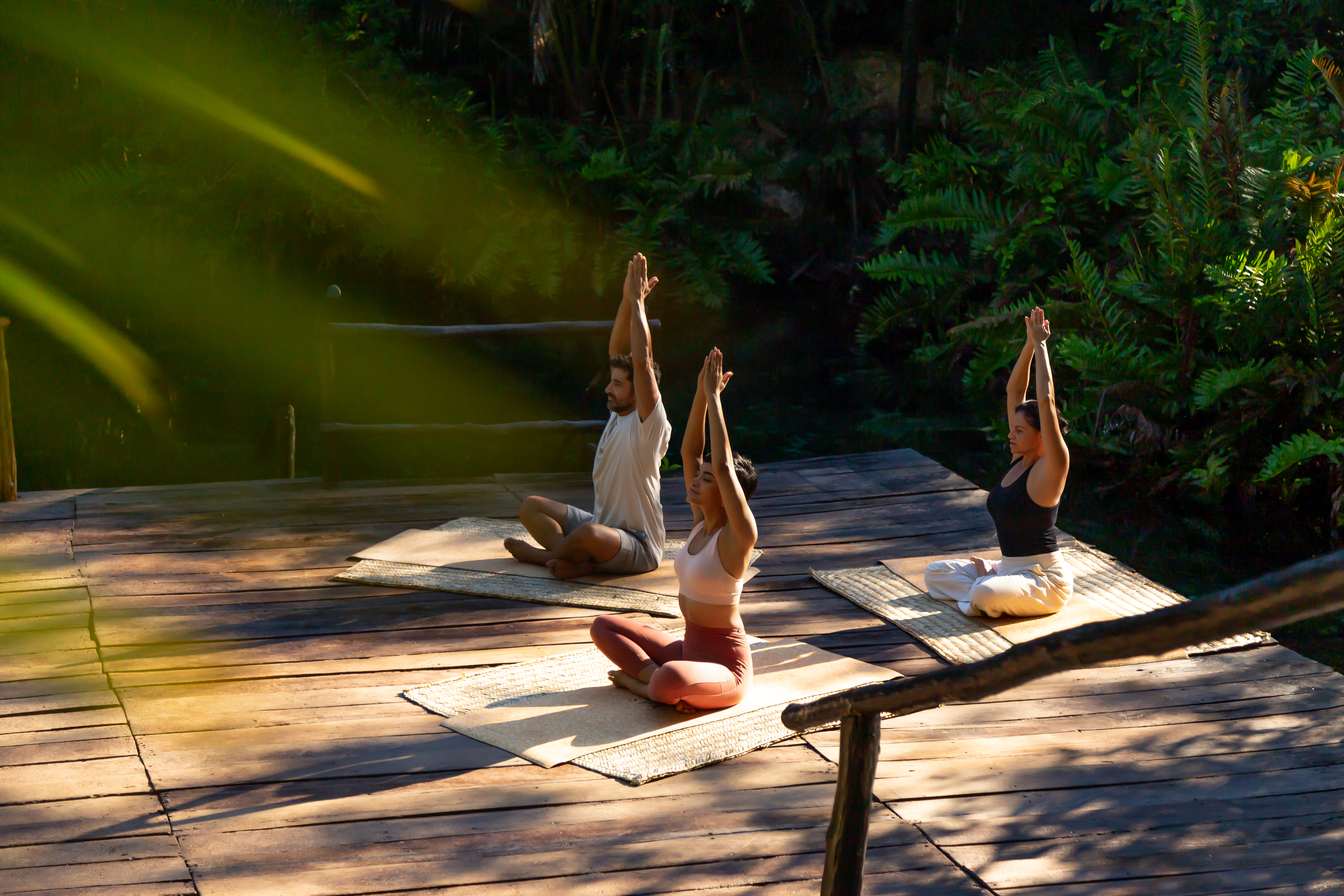 a group of people sitting on mats with their hands up