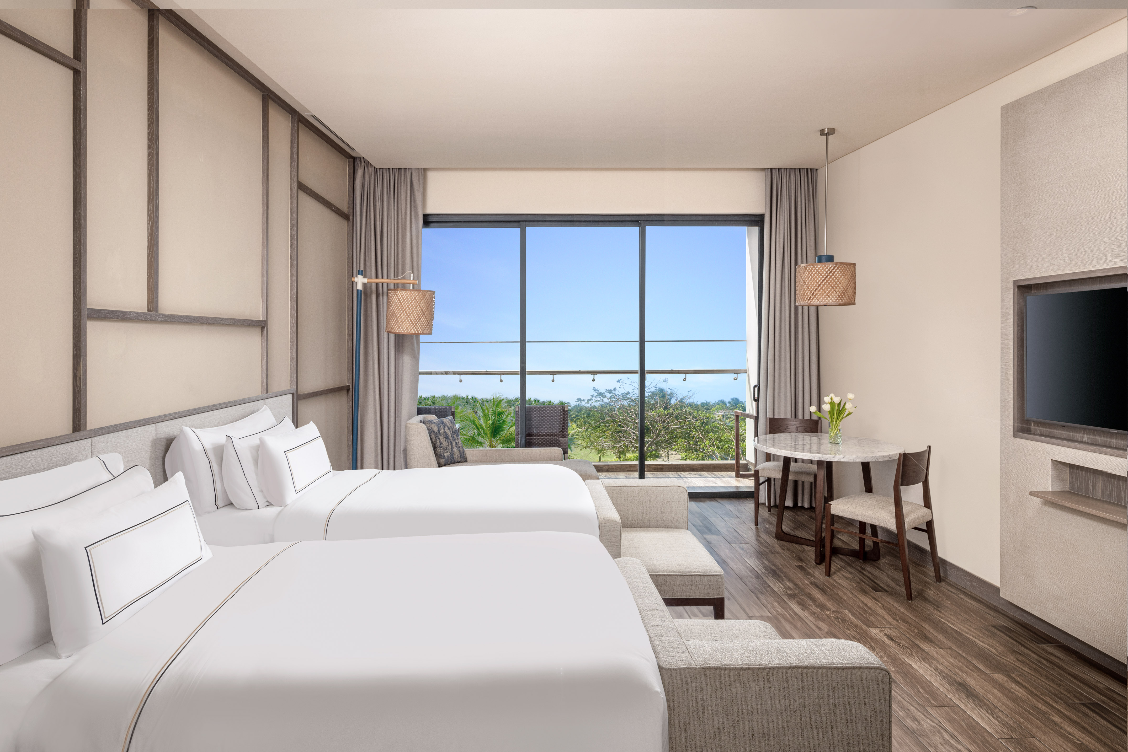 Resort room with two beds, private balcony, and lush green landscape.