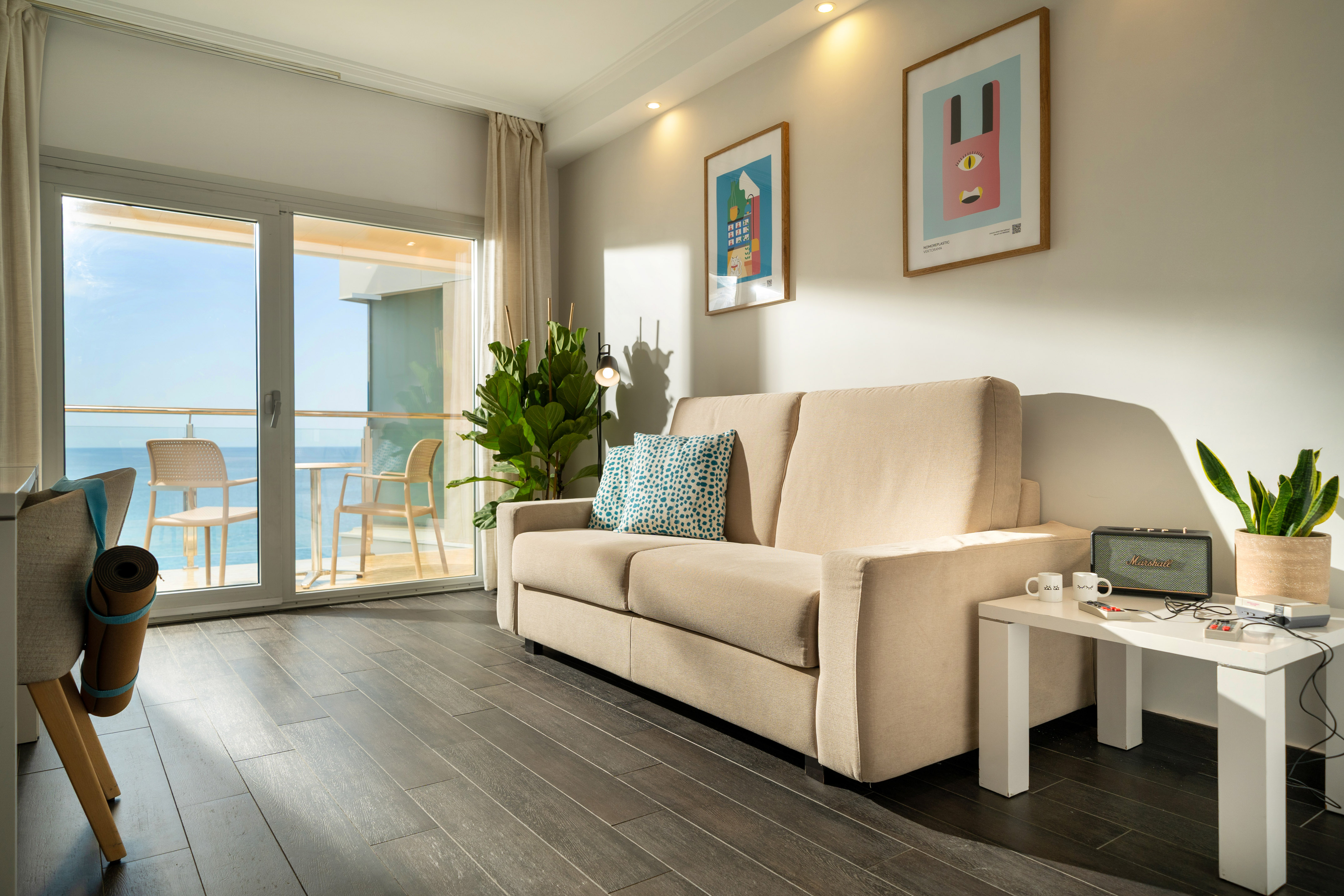Coastal apartment living room with ocean view balcony, beige sofa, and modern decor.