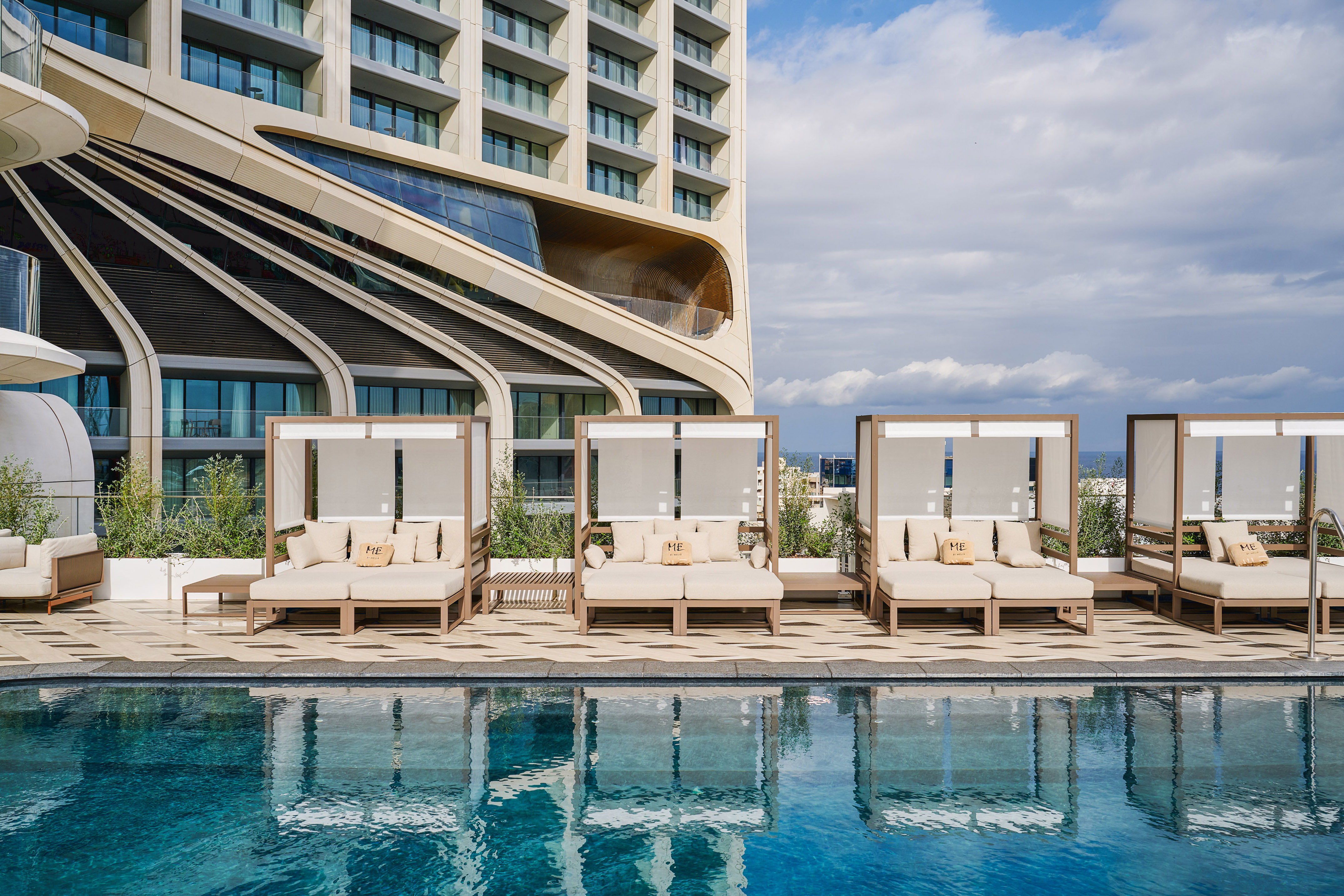 Luxury resort pool with modern cabanas and a contemporary architectural hotel.
