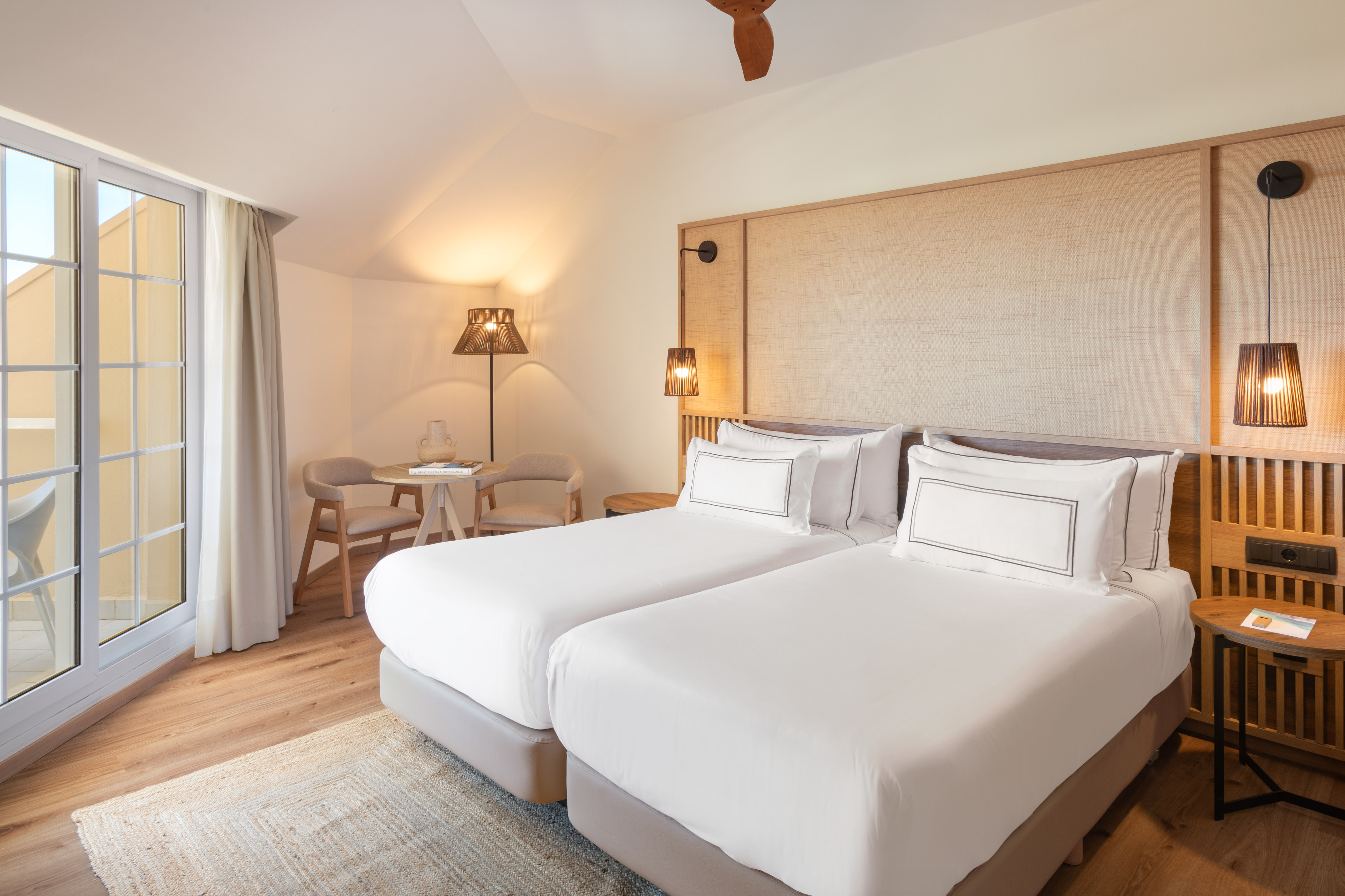 Bright hotel room with twin beds, modern decor, and balcony access.