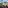 White table and chairs on balcony with coastal town, mountains, and sea view.