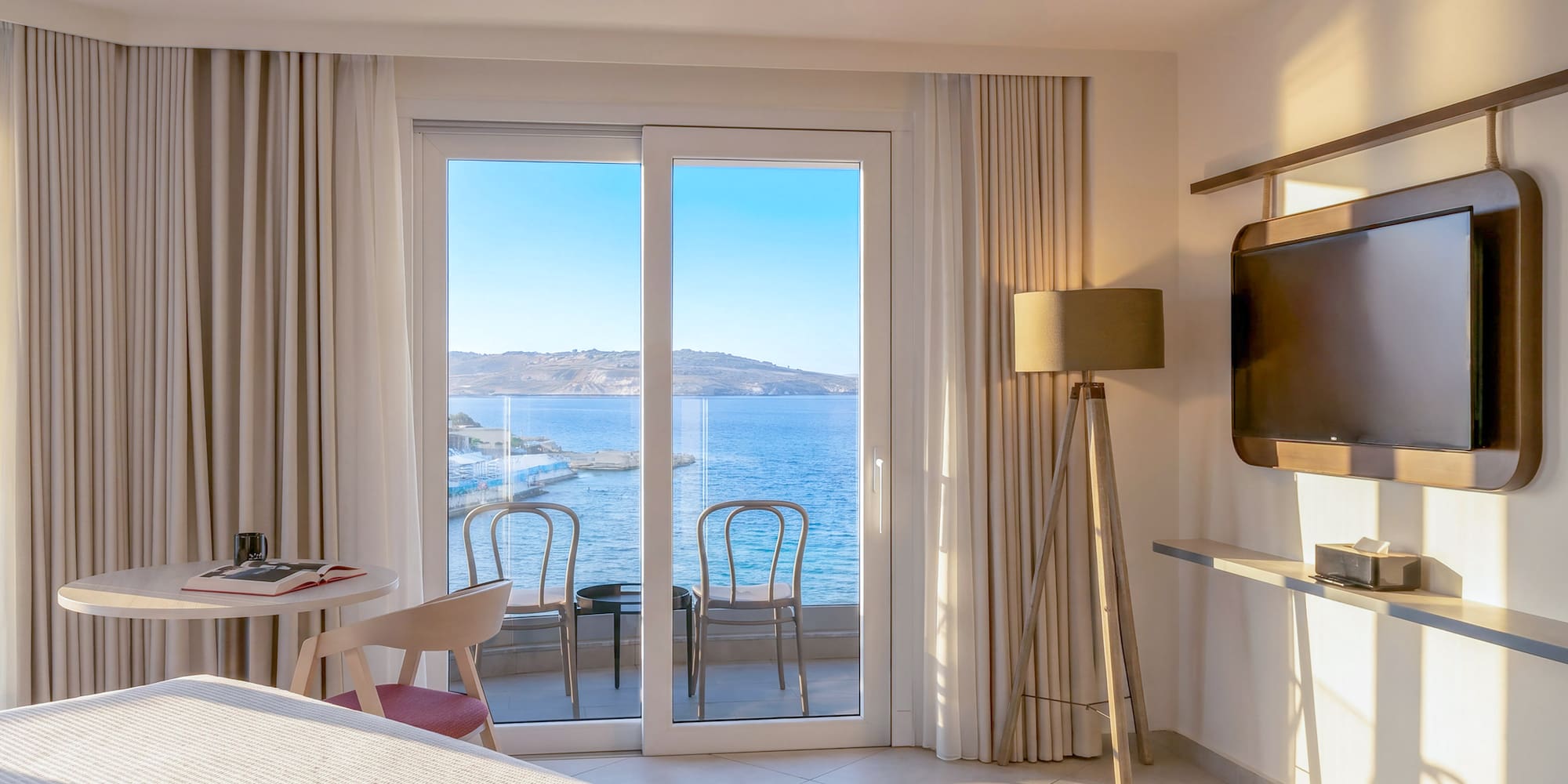 Hotel room with sea view balcony and modern interior design.