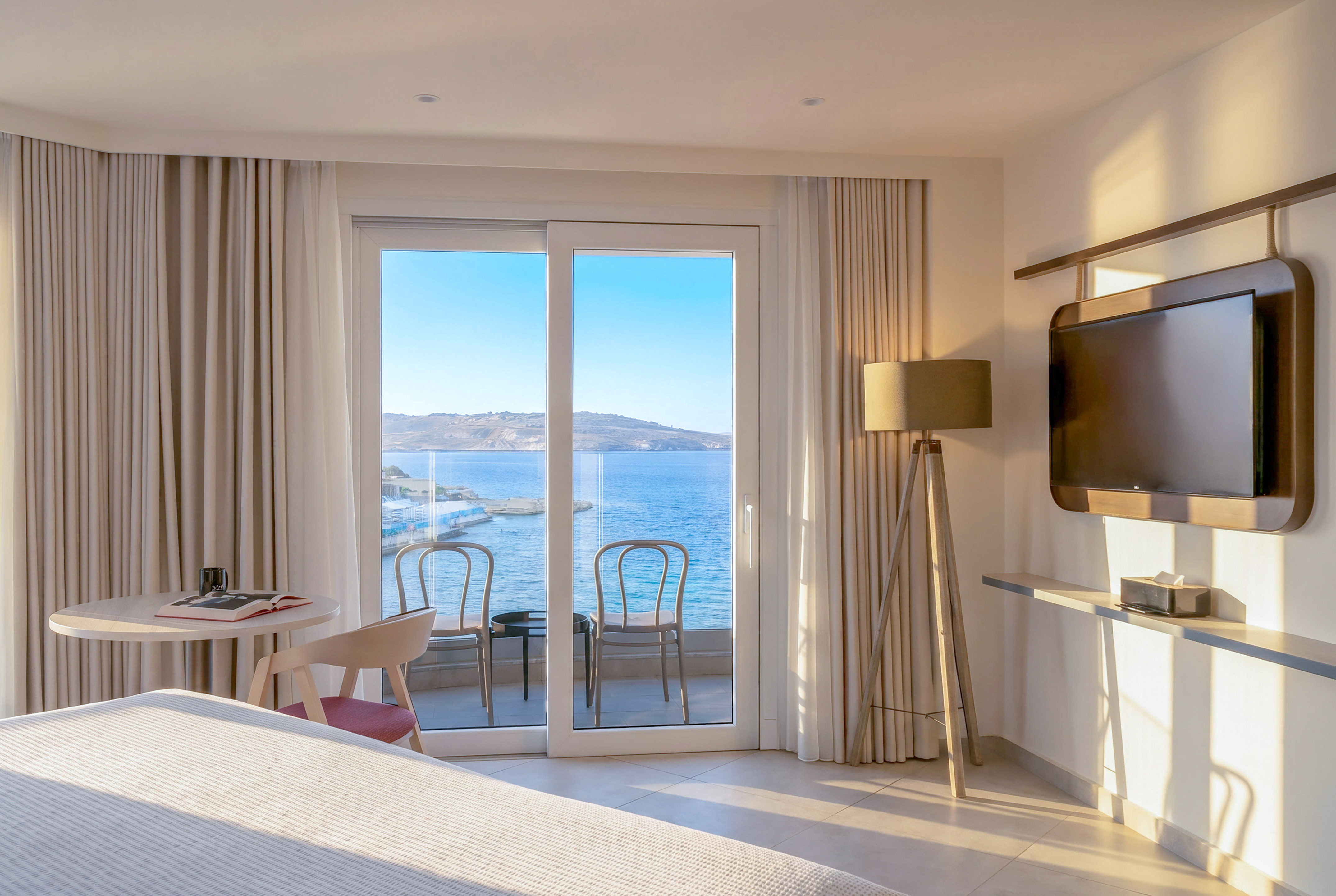 Hotel room with sea view balcony and modern interior design.