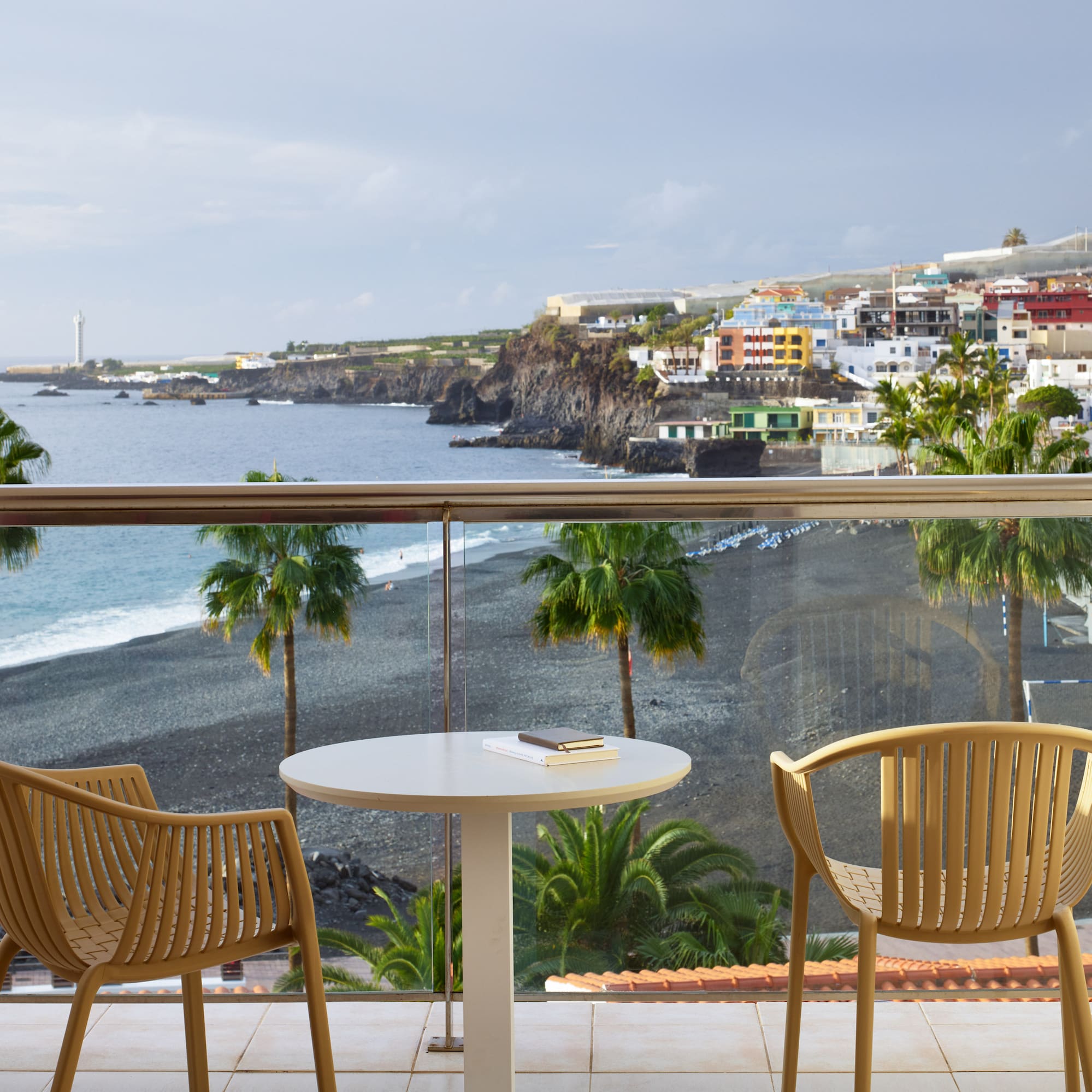 a table and chairs on a balcony overlooking a beach