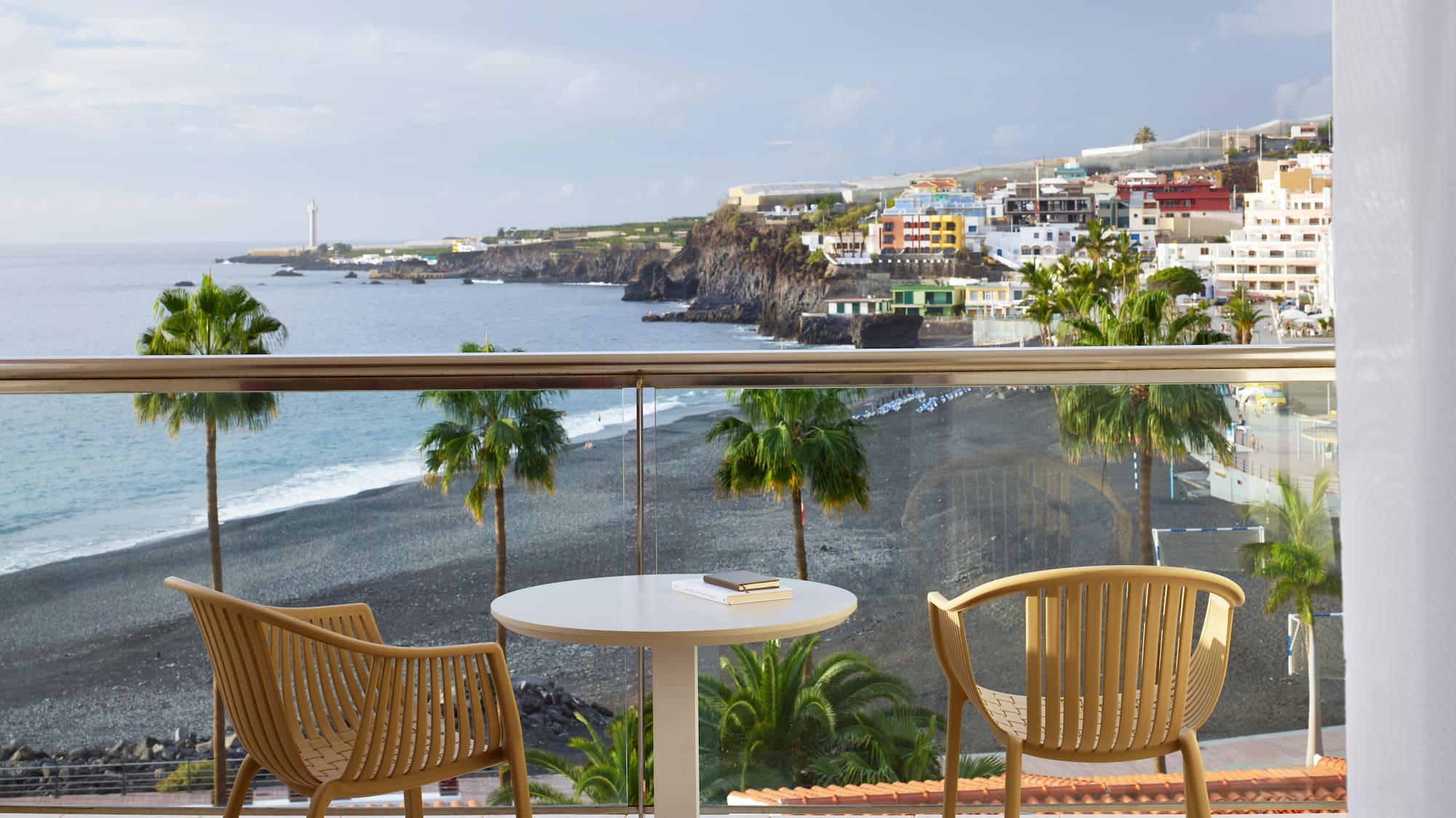 a table and chairs on a balcony overlooking a beach