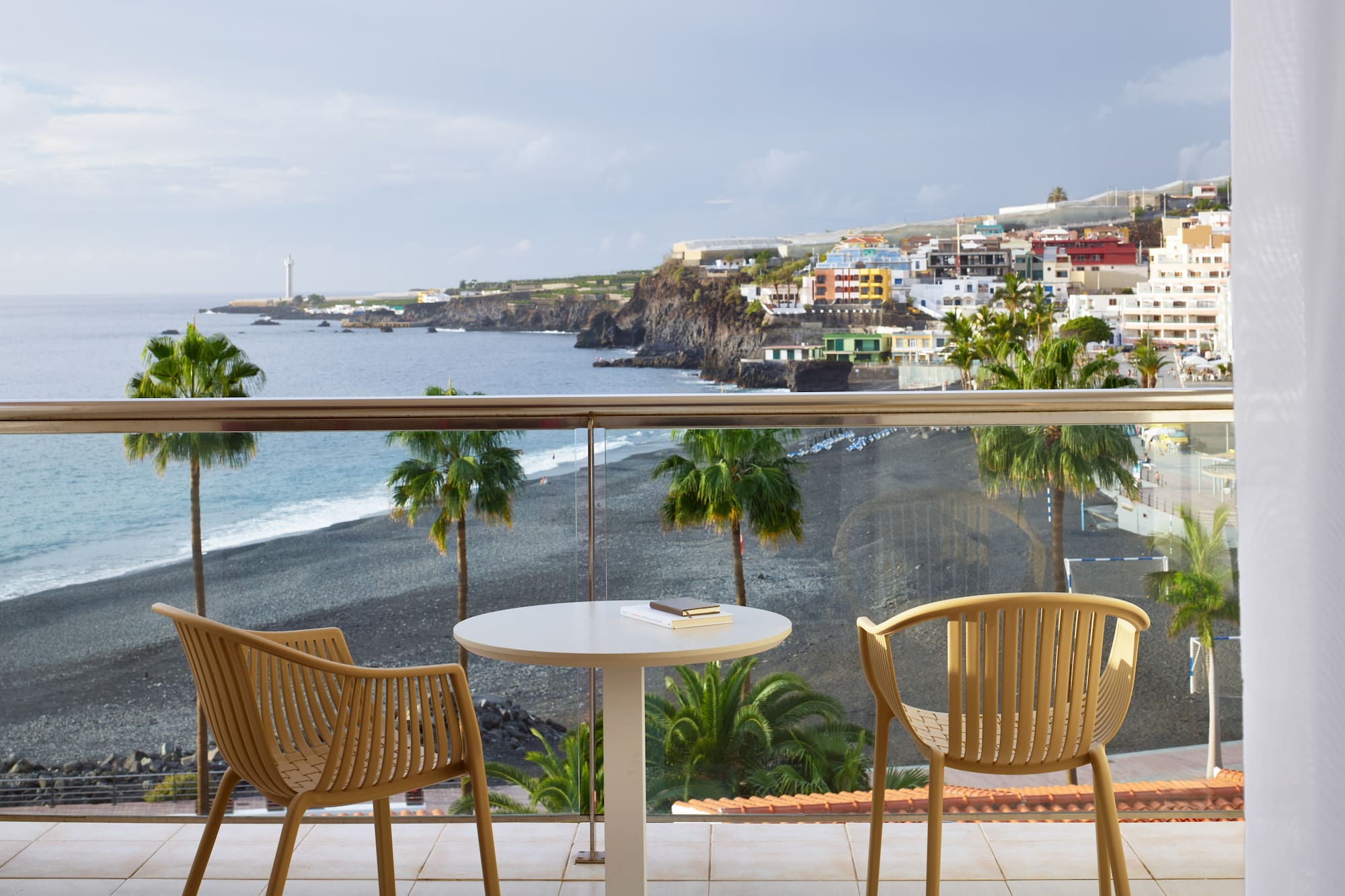 a table and chairs on a balcony overlooking a beach
