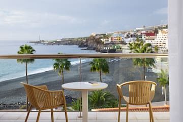 a table and chairs on a balcony overlooking a beach