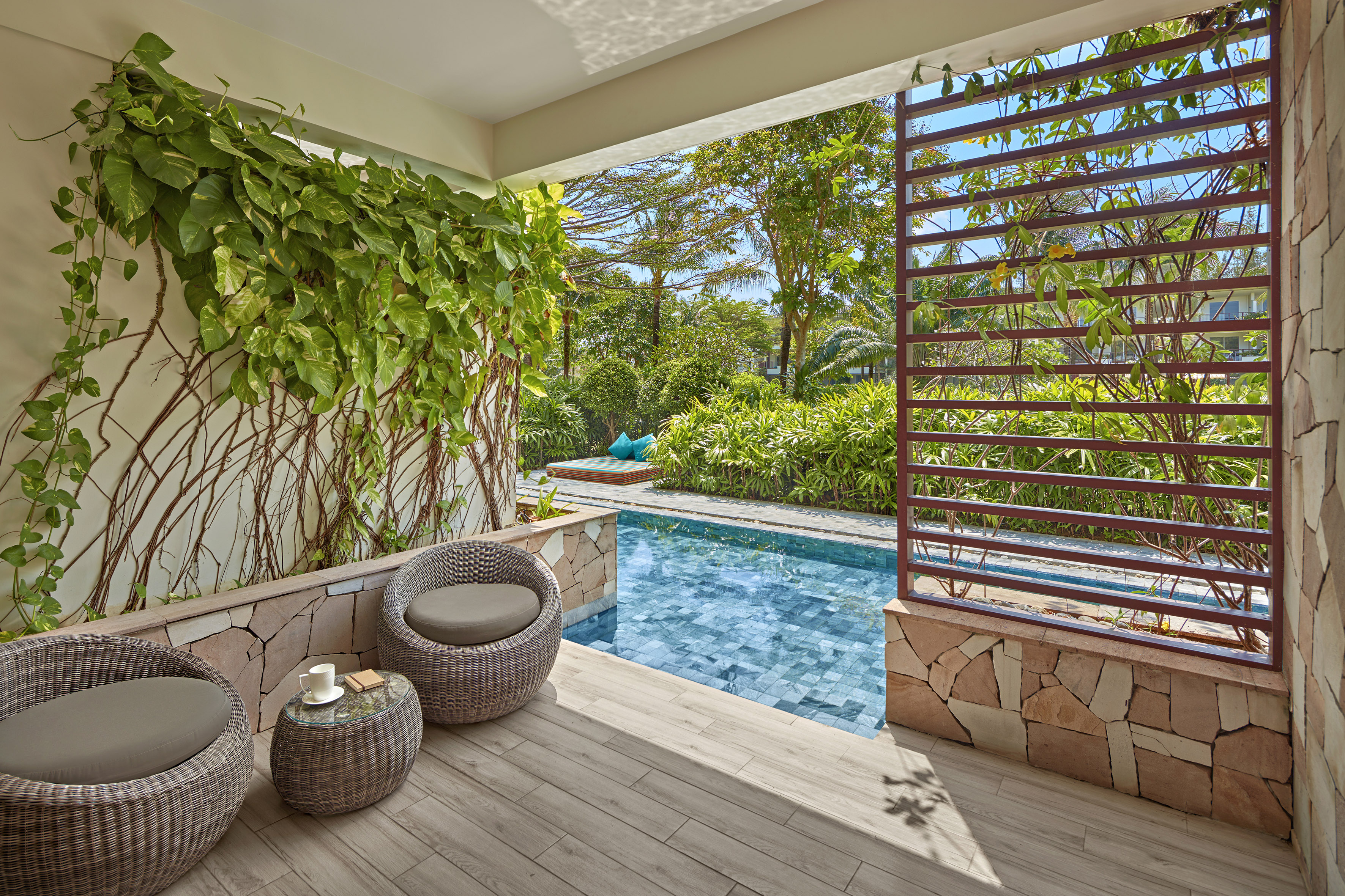 Tropical villa patio with private plunge pool, wicker chairs, and lush garden.