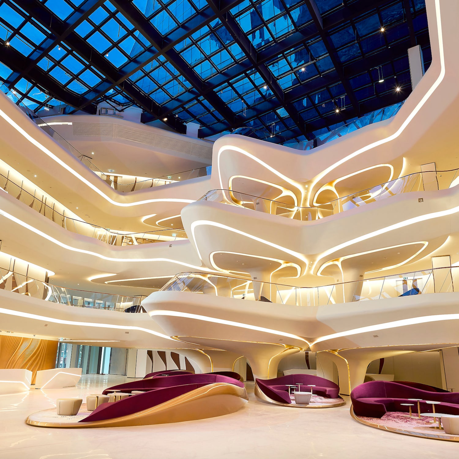 Futuristic atrium with glowing curved levels, glass roof, and luxury seating.