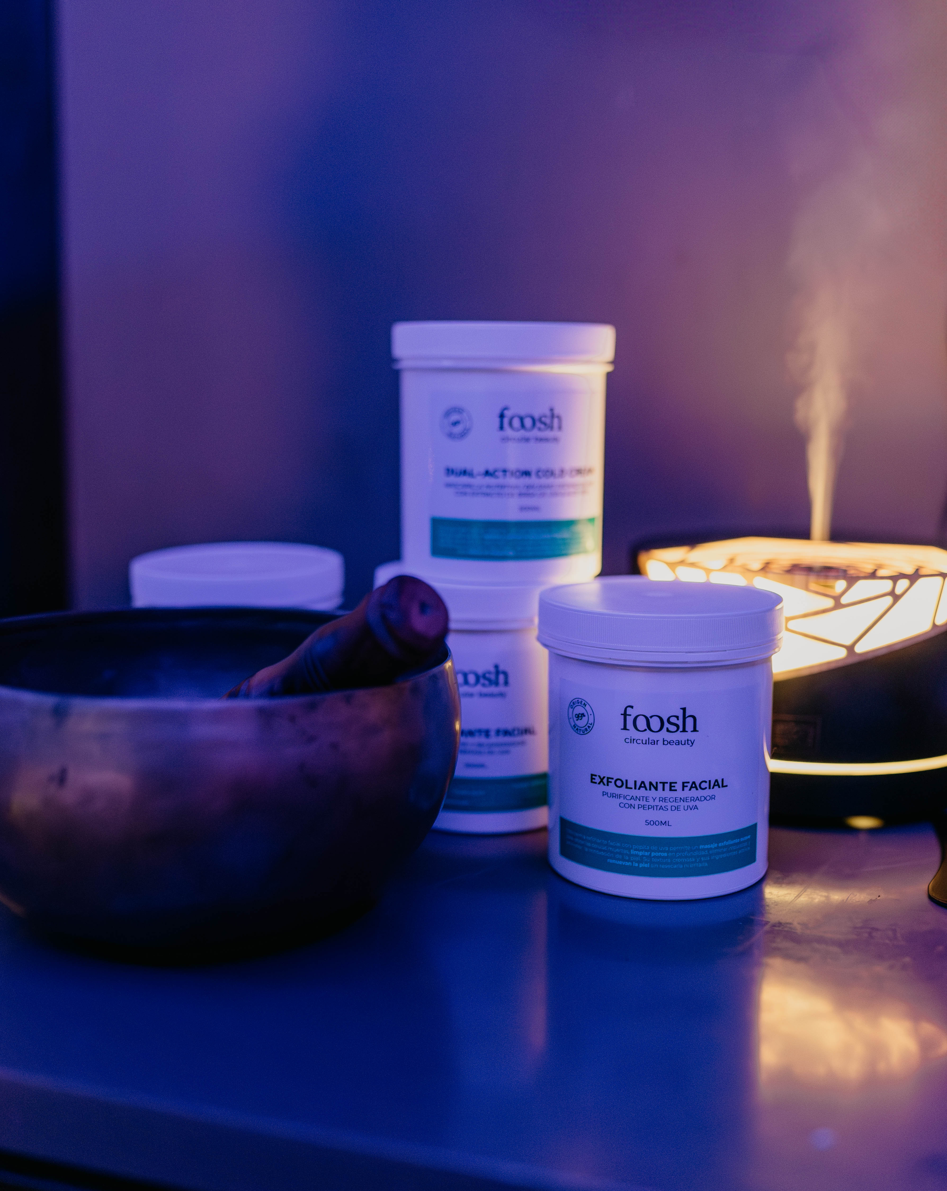White Foosh Exfoliante Facial jar, spa diffuser, and singing bowl.