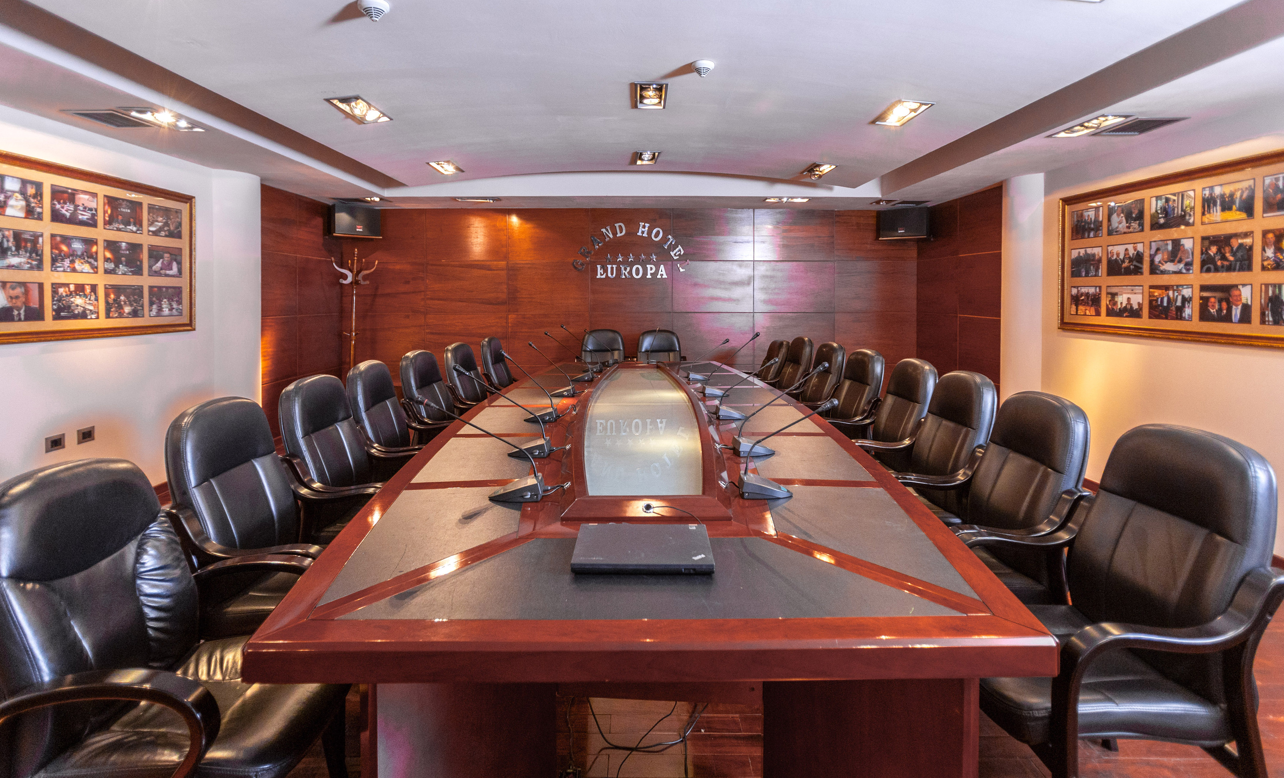 Grand Hotel Europa conference room with long wooden table, leather chairs, and microphones.