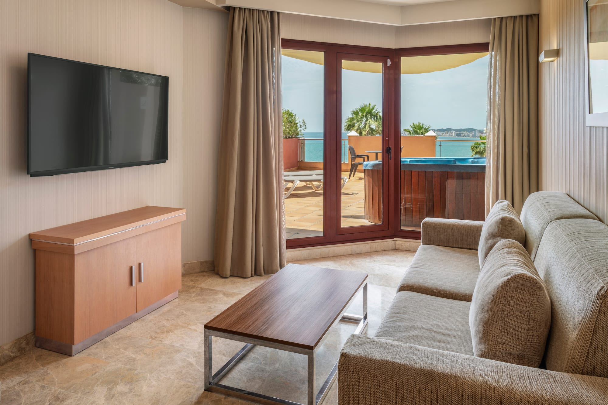 Luxury hotel suite living room with sea view balcony and hot tub.