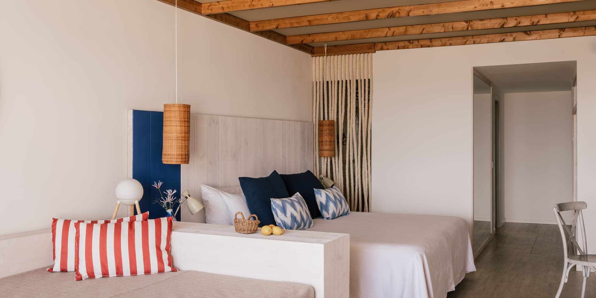 Dormitorio luminoso con cama doble, vigas de madera y diseño mediterráneo.