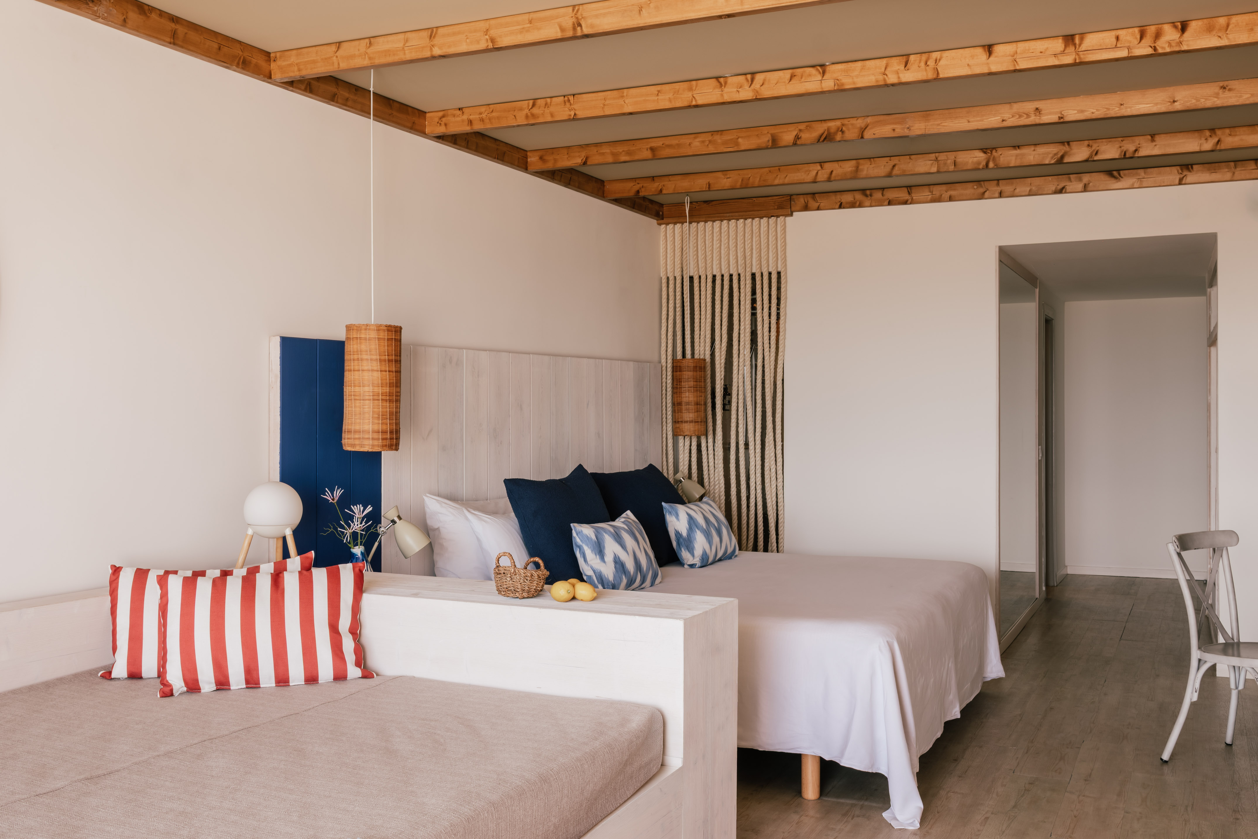 Dormitorio luminoso con cama doble, vigas de madera y diseño mediterráneo.
