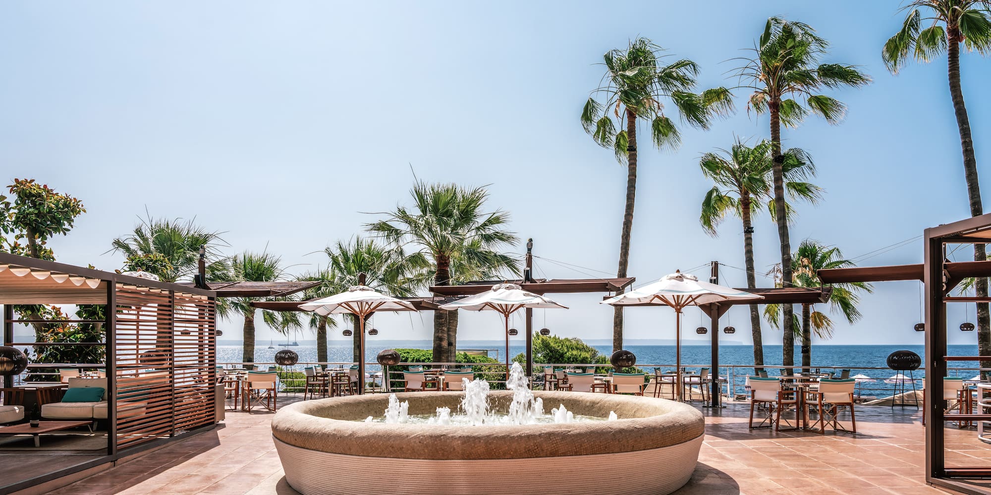 a water fountain with umbrellas and chairs on a patio