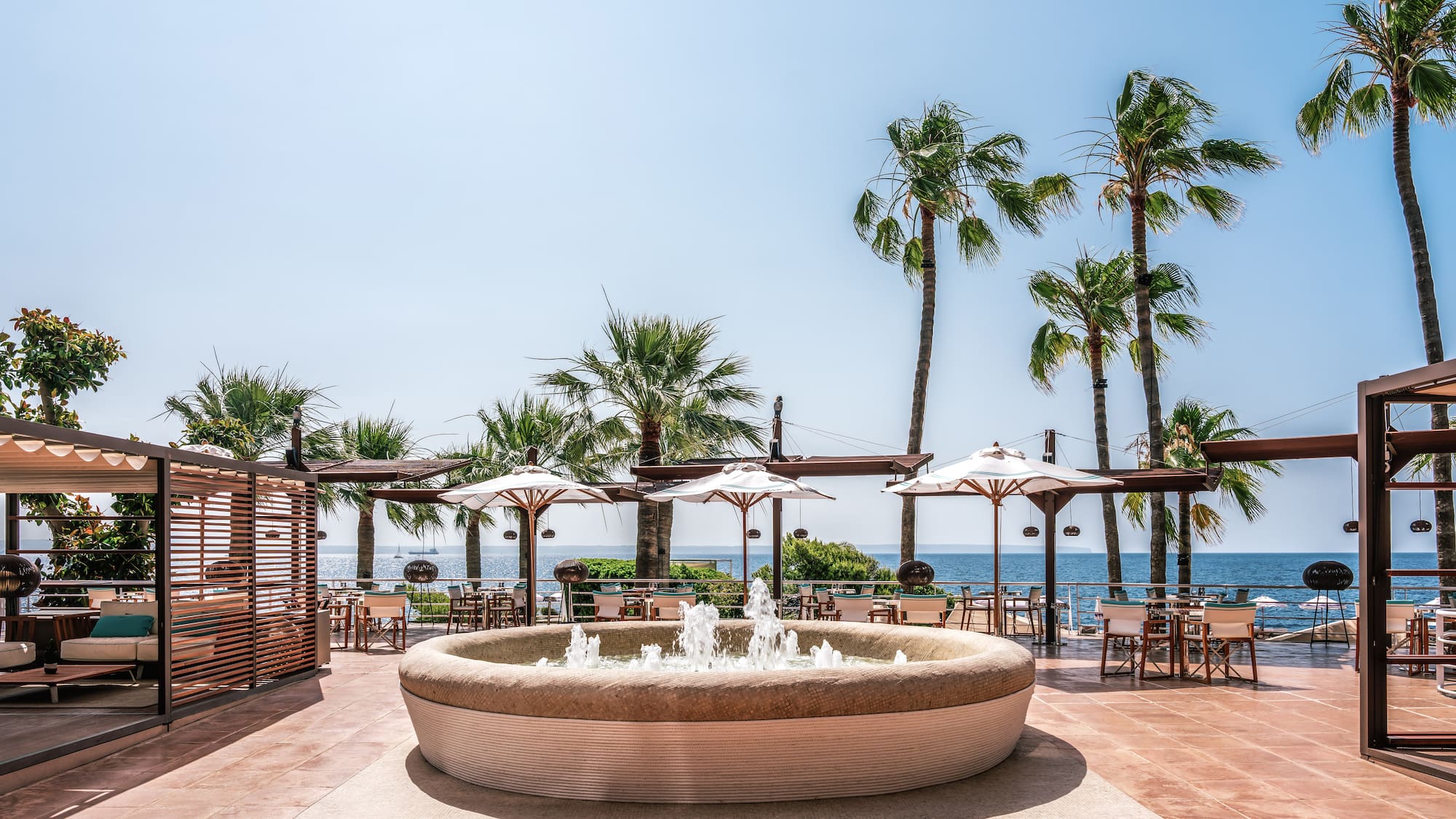 a water fountain with umbrellas and chairs on a patio