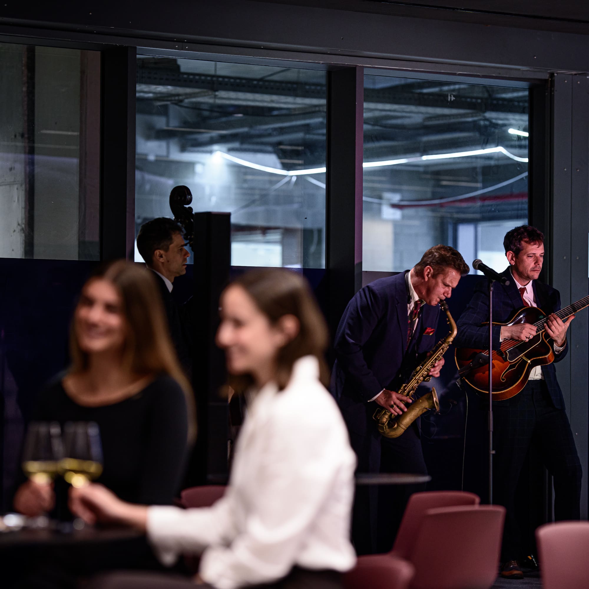Músicos en vivo tocando saxofón y guitarra en evento corporativo.