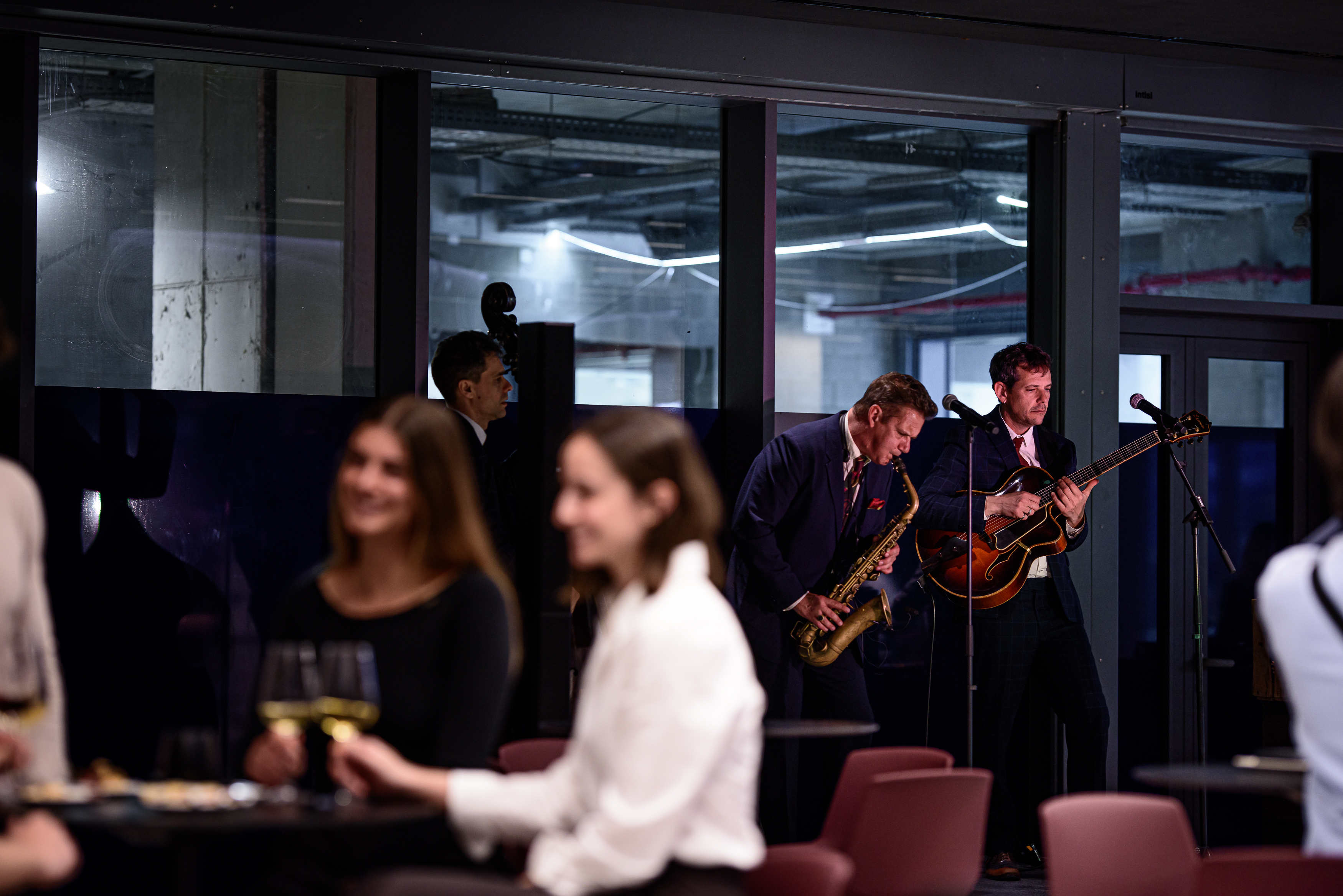 Músicos en vivo tocando saxofón y guitarra en evento corporativo.