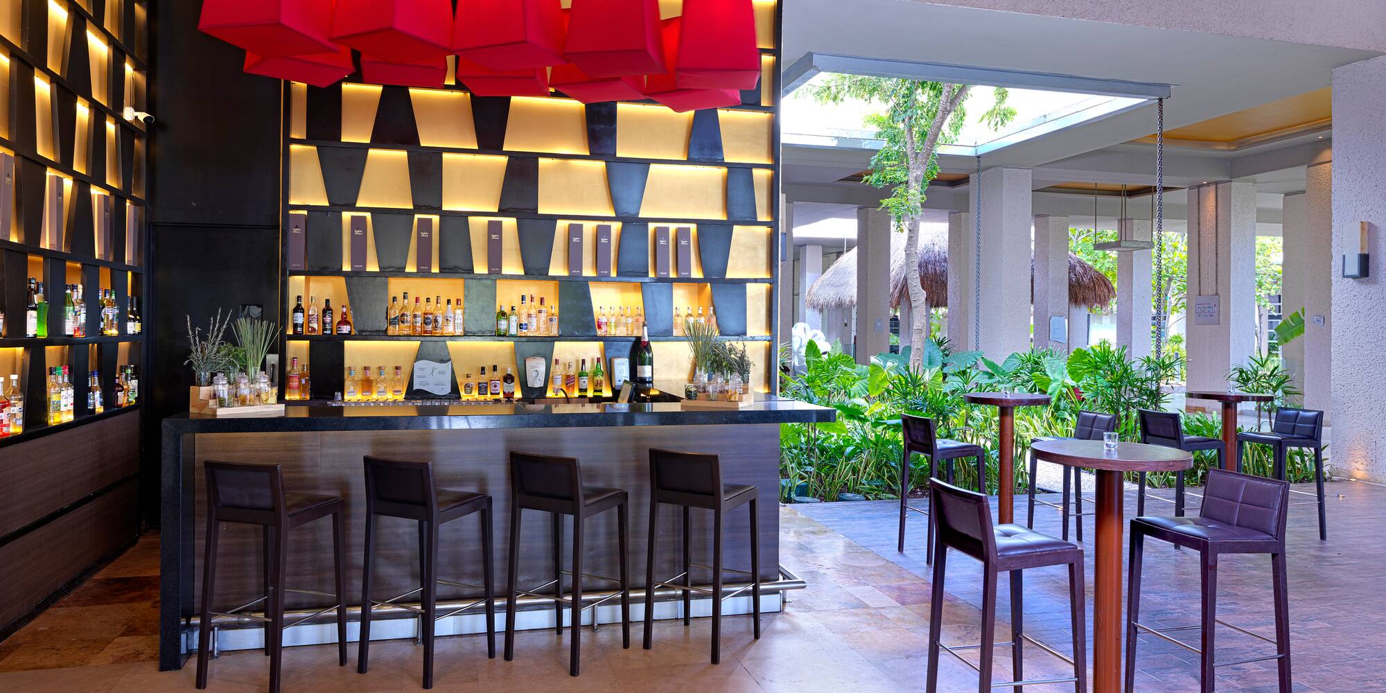 a bar with red lamps and chairs