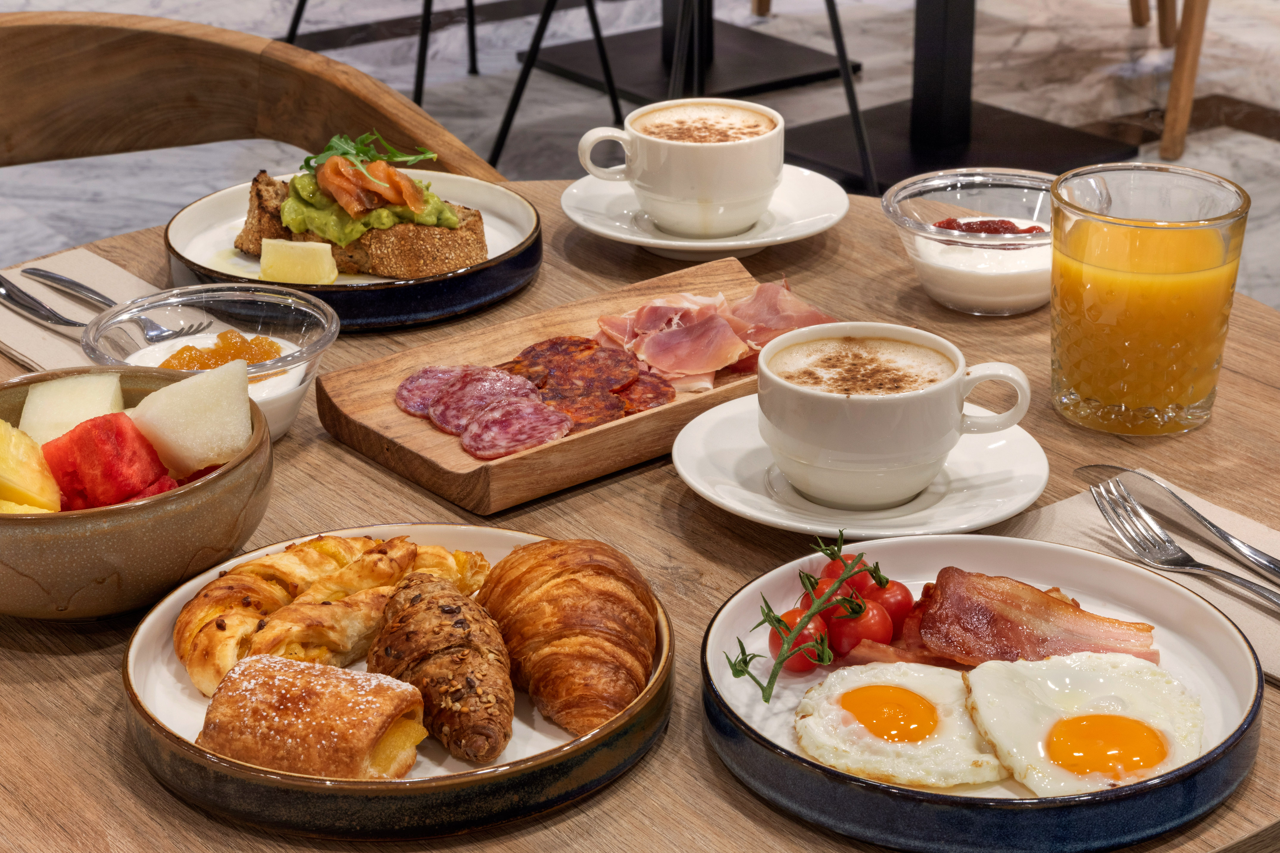 Variado desayuno: café, huevos, tocino, bollería, fruta, tostada, embutidos