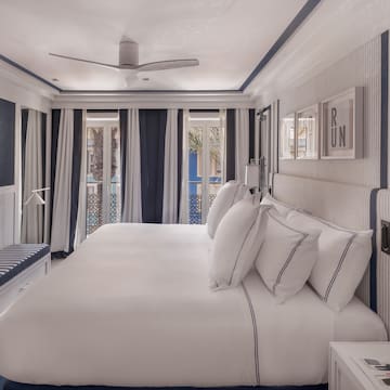 a bed with white sheets and blue striped walls