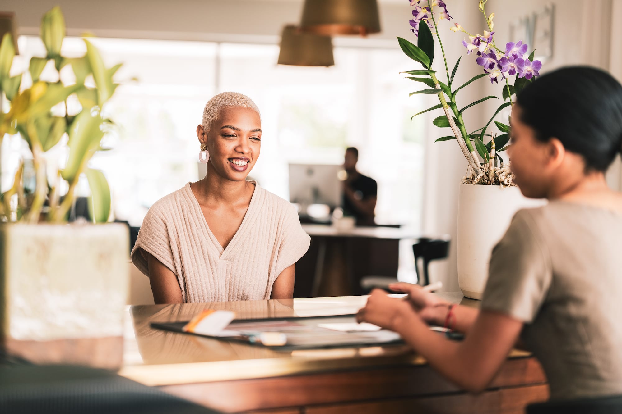 a woman sitting at a table with another woman smiling
