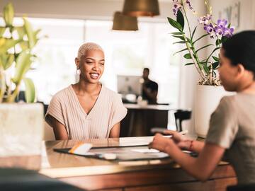 a woman sitting at a table with another woman smiling