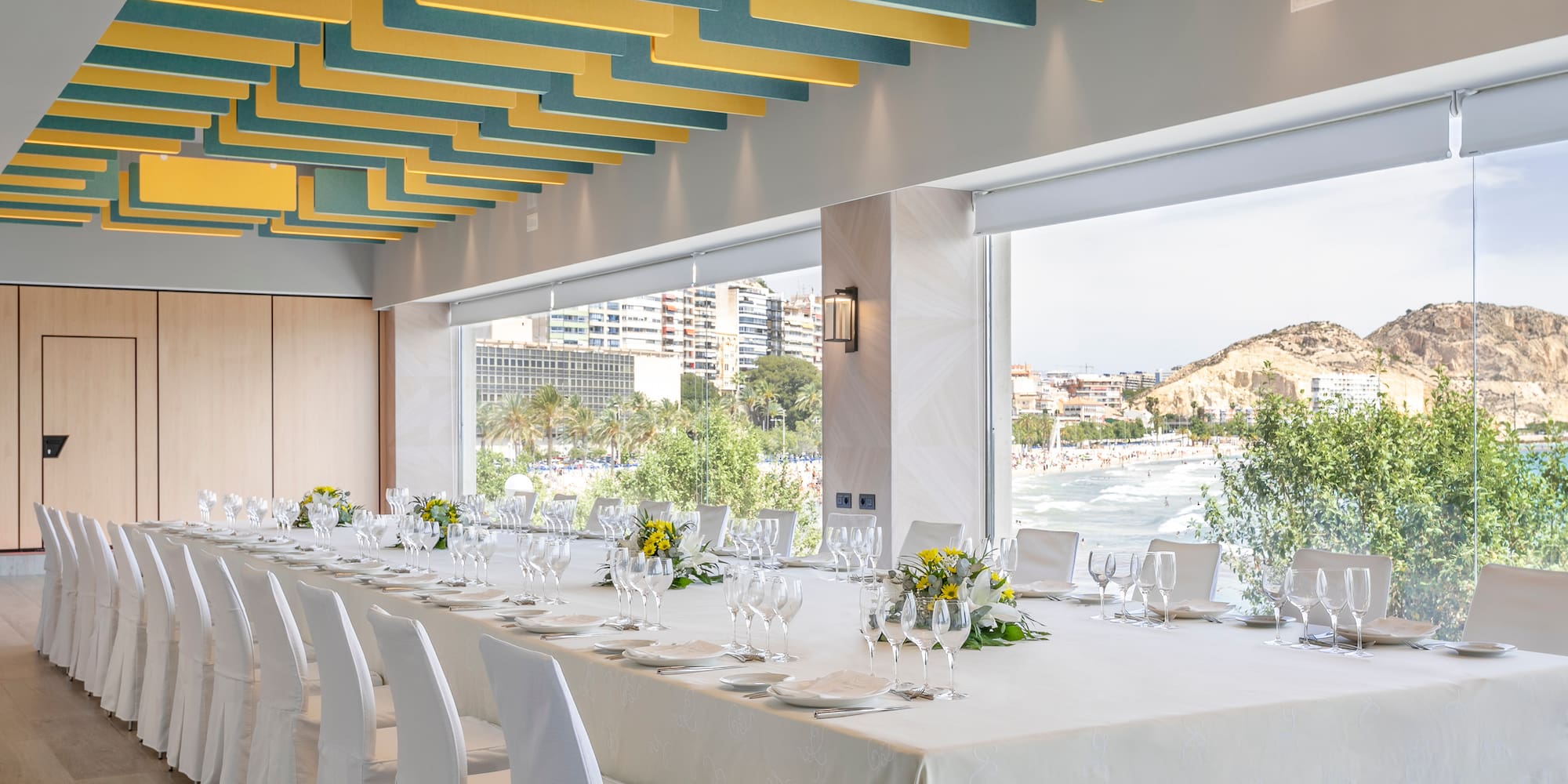 a long table with white cloth and white chairs