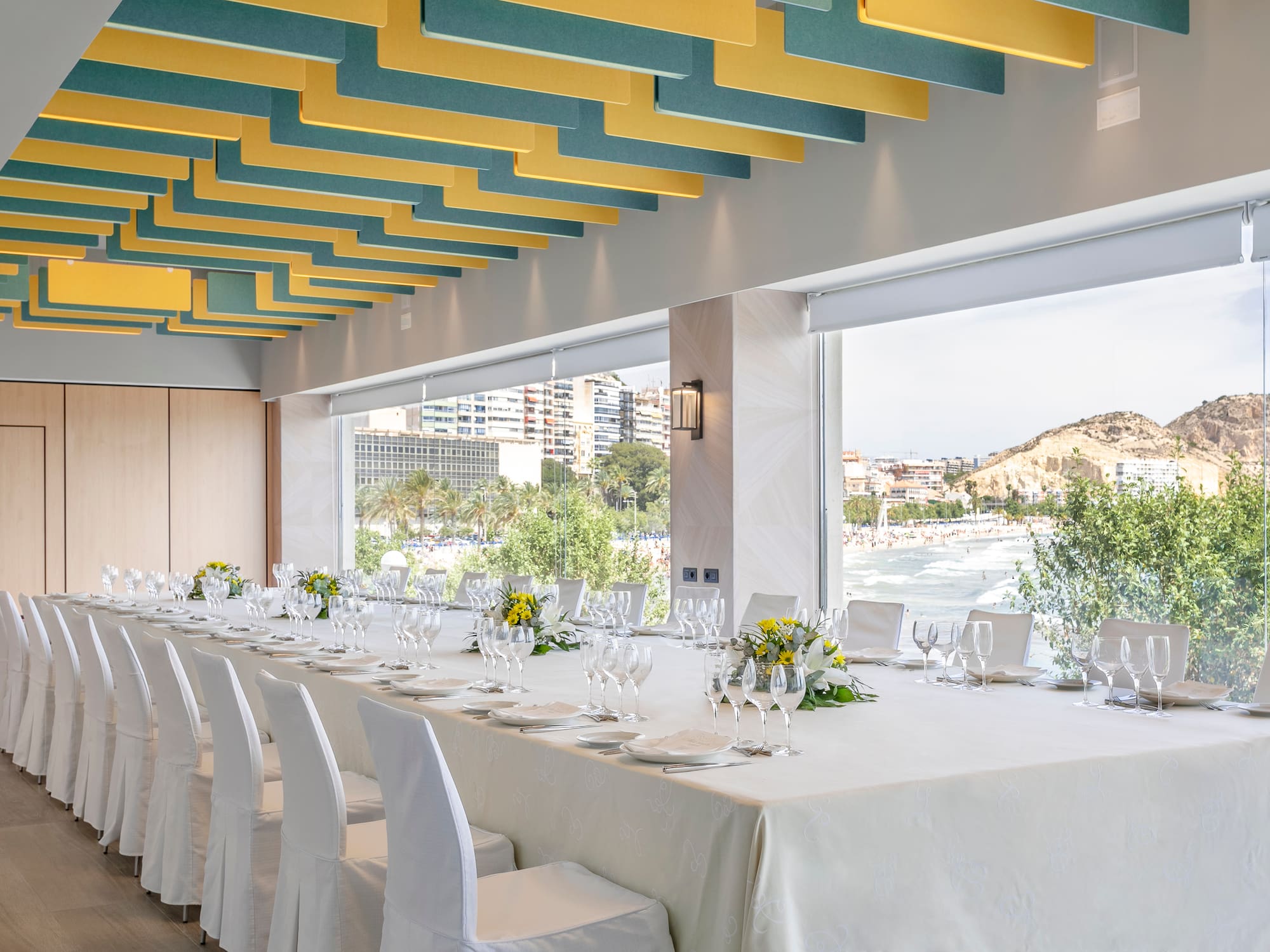 a long table with white cloth and white chairs
