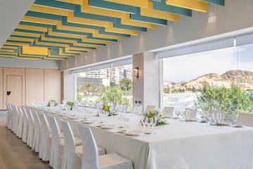 a long table with white cloth and white chairs