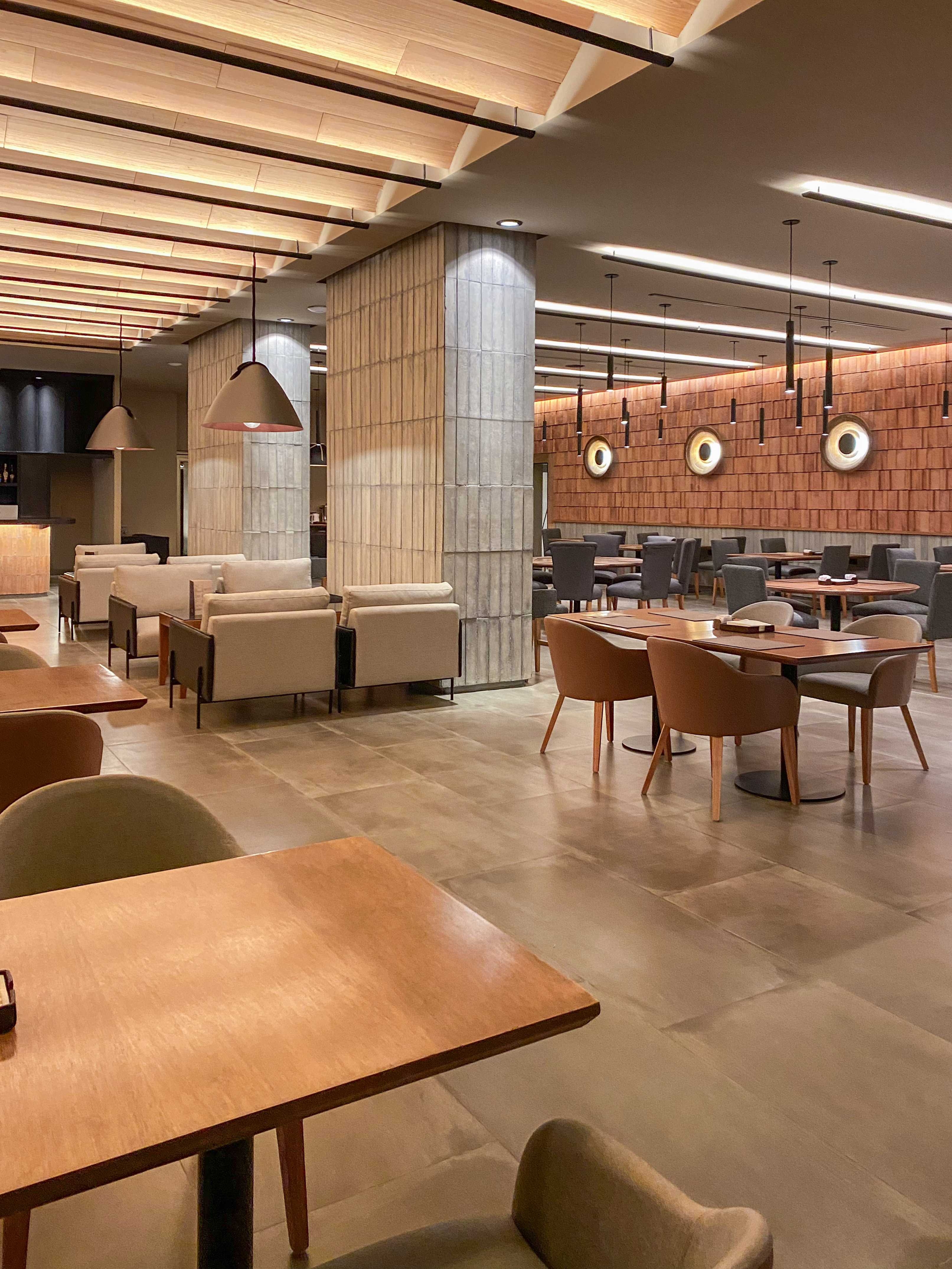 Modern restaurant interior with wooden ceiling, cozy lounge, and dining tables.