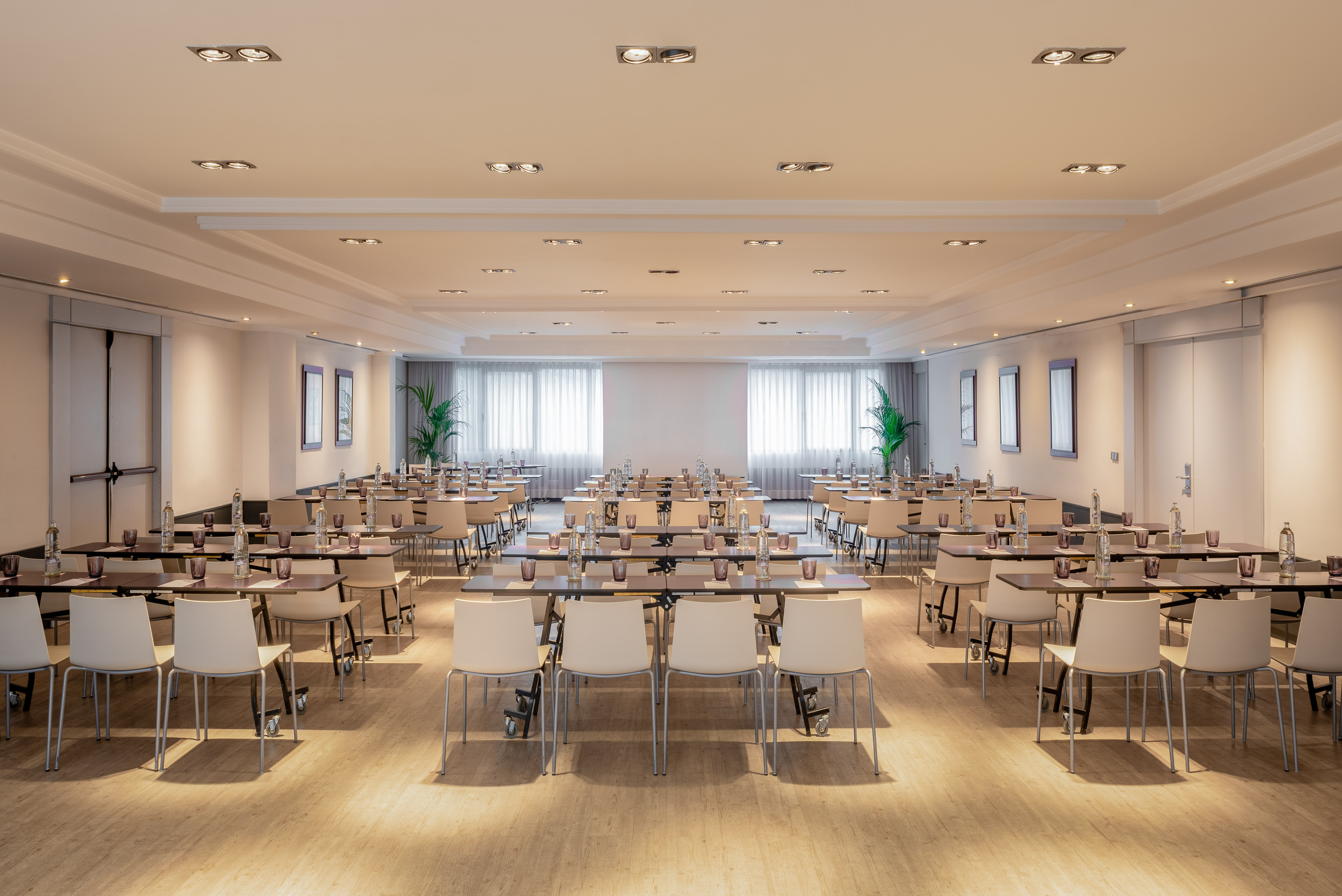 Bright, empty conference room with tables, chairs, and plants, ready for an event.