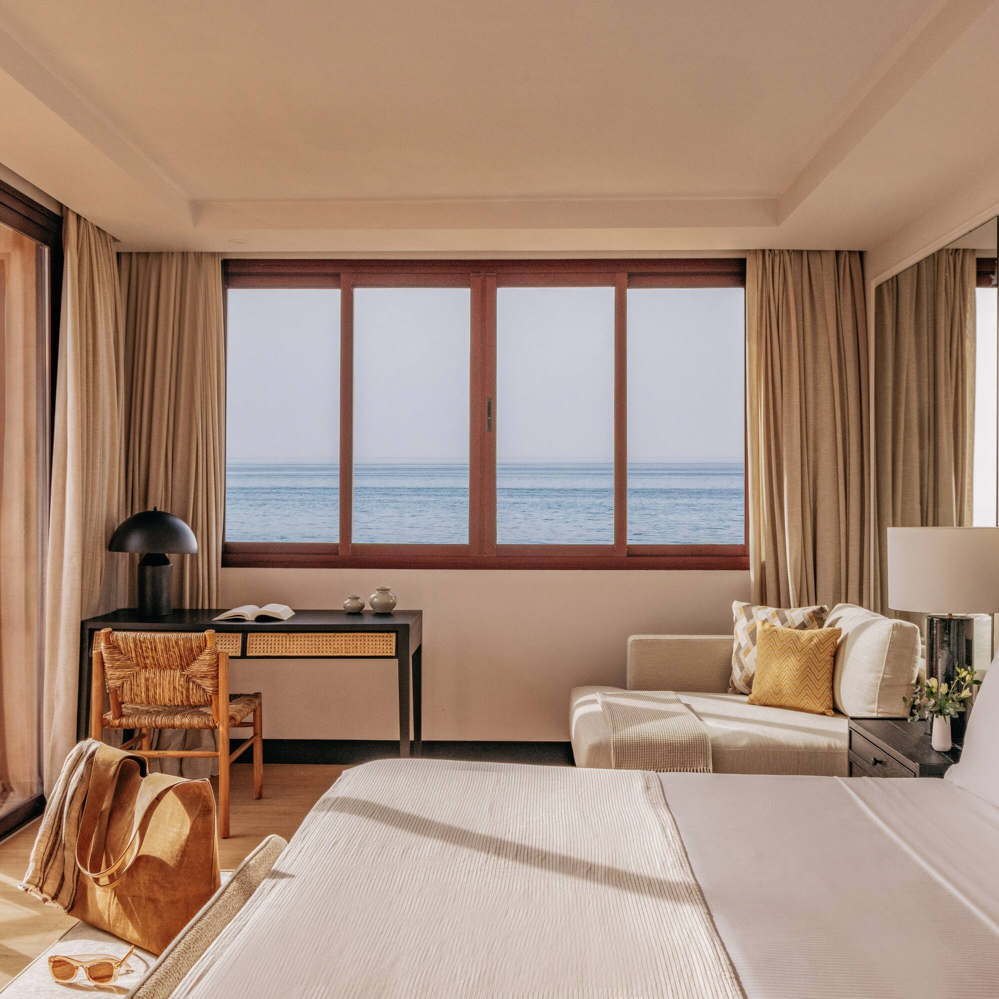 Luxury hotel room with panoramic ocean view, modern decor, and bright interior.