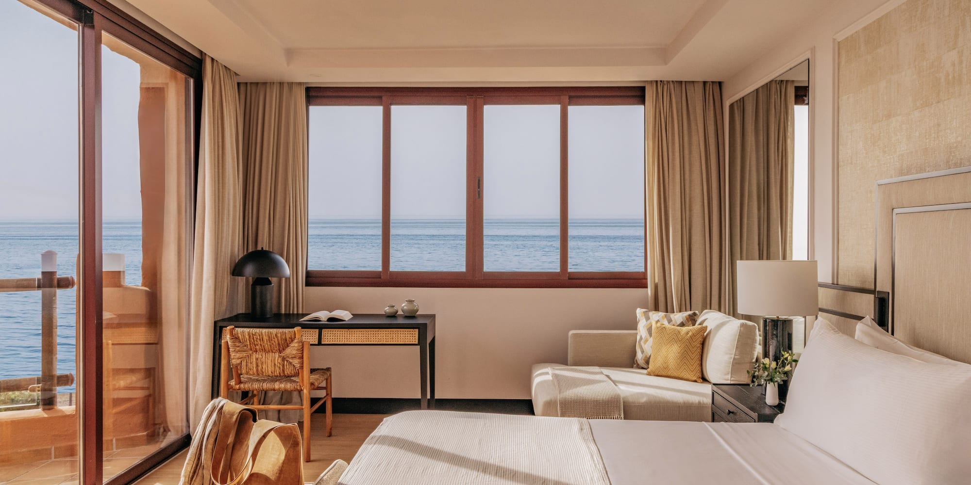Luxury hotel room with panoramic ocean view, modern decor, and bright interior.