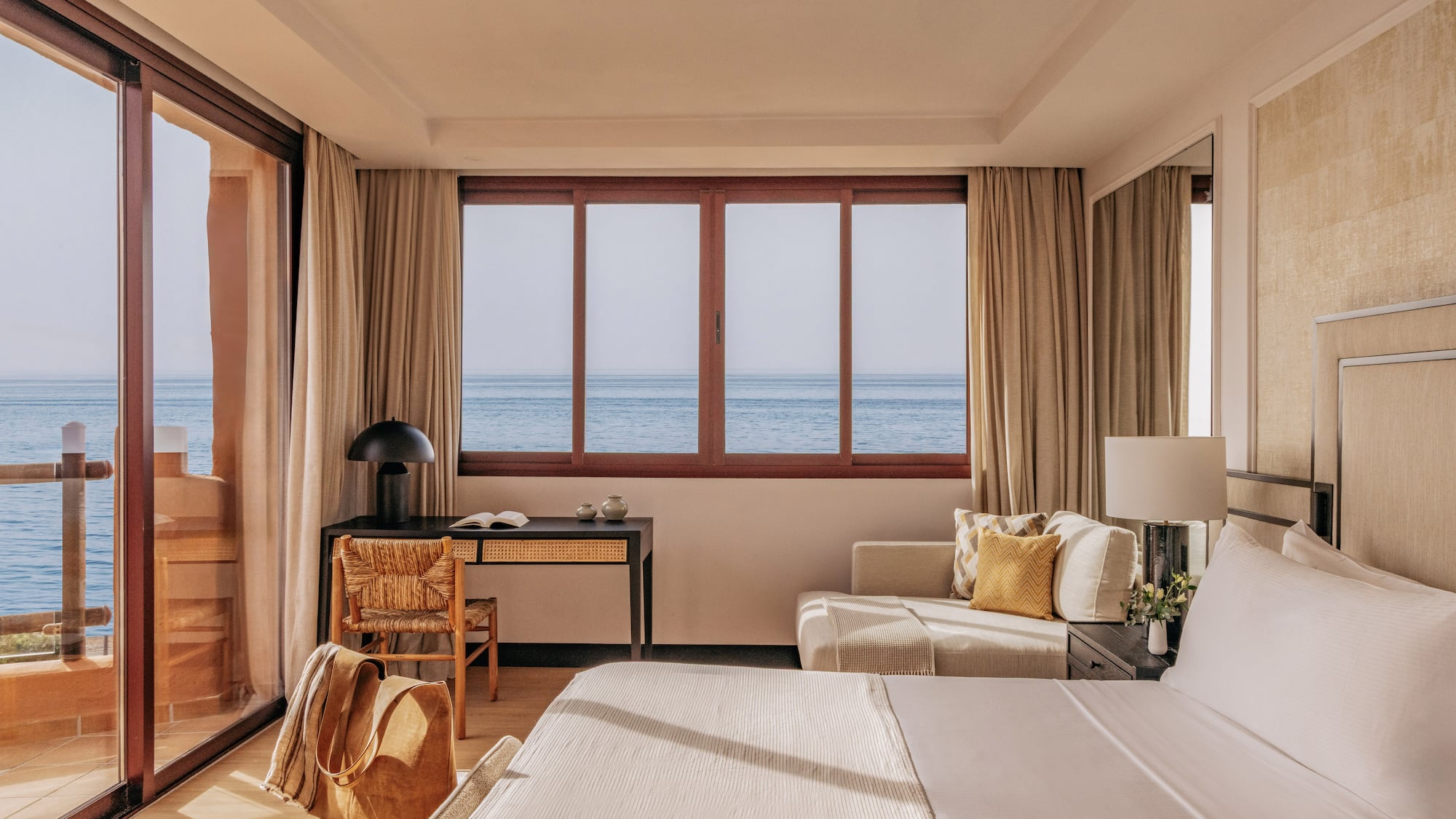 Luxury hotel room with panoramic ocean view, modern decor, and bright interior.