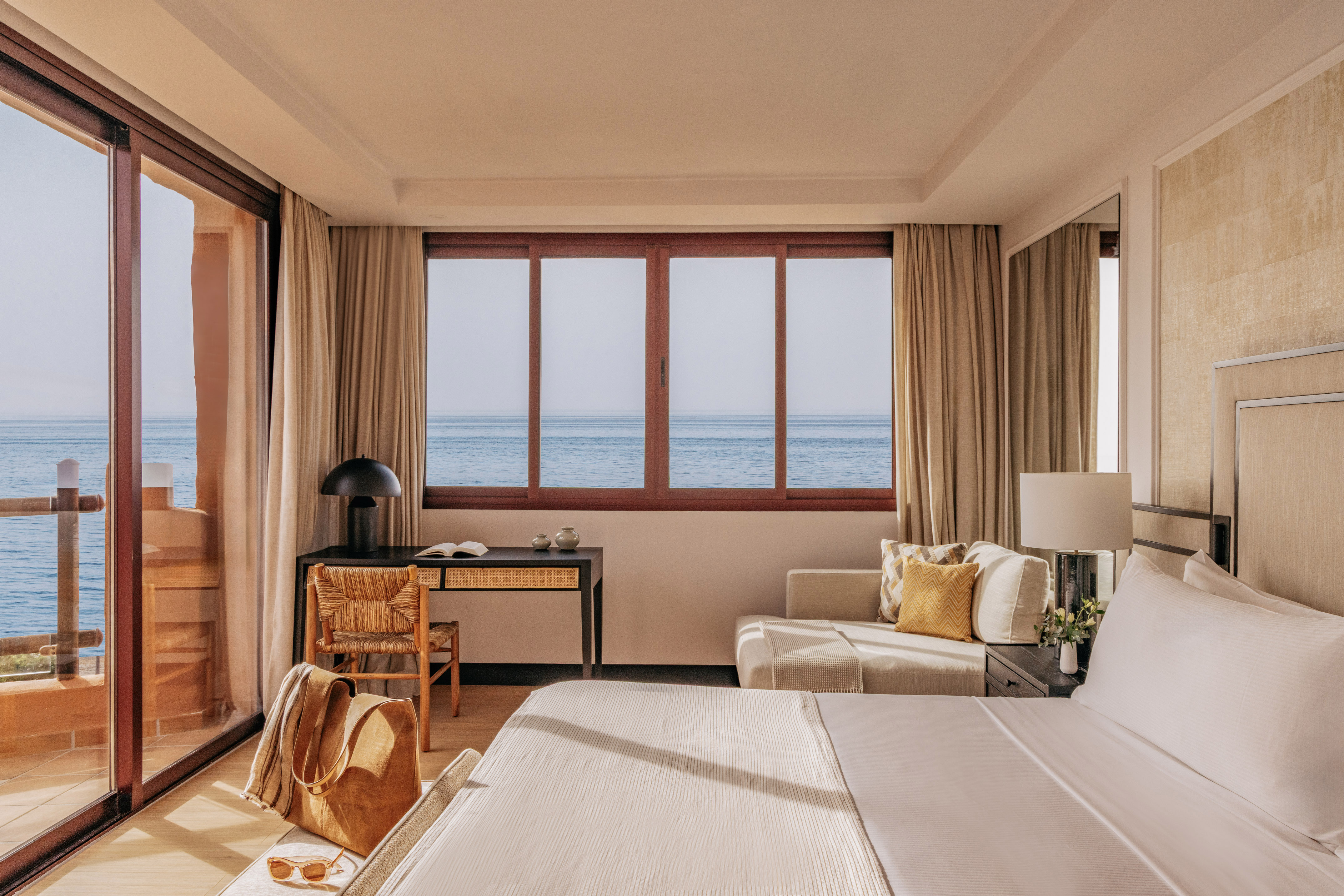 Luxury hotel room with panoramic ocean view, modern decor, and bright interior.