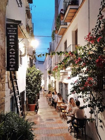 people sitting at tables in a narrow alley between buildings