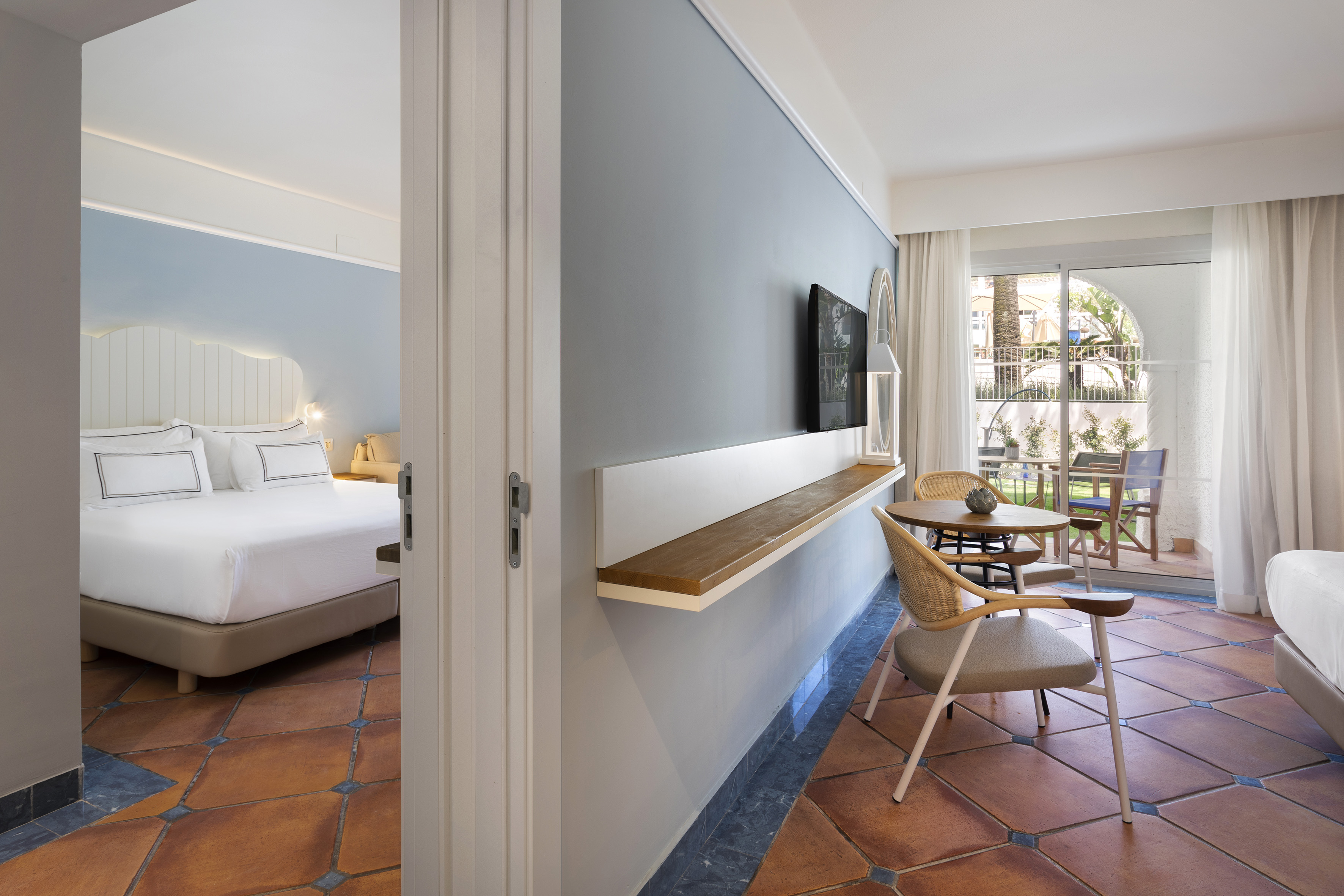 Modern hotel room with separate bedroom, living area, terracotta floor, and outdoor patio.