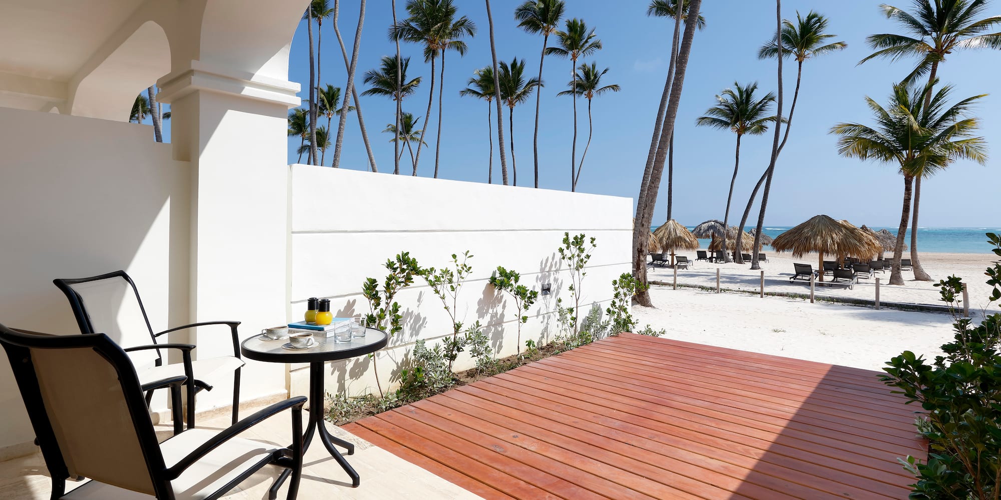 a deck with a table and chairs on a beach