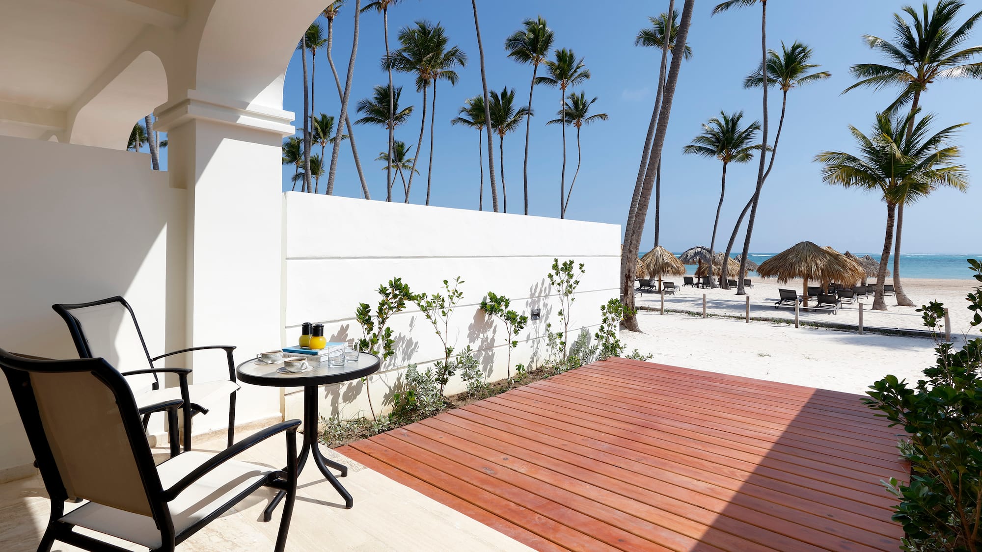 a deck with a table and chairs on a beach