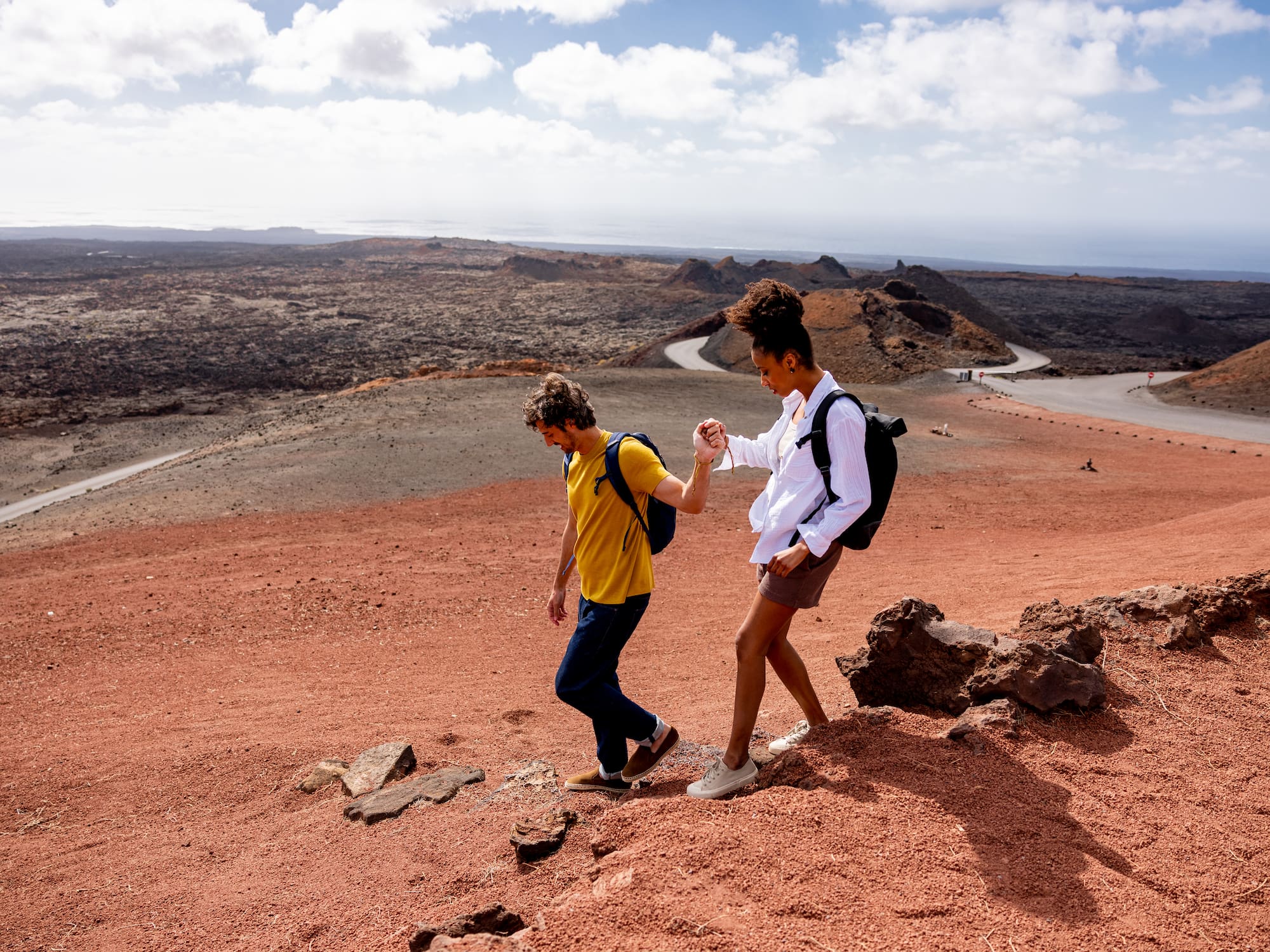 a man and woman walking on a rocky hill