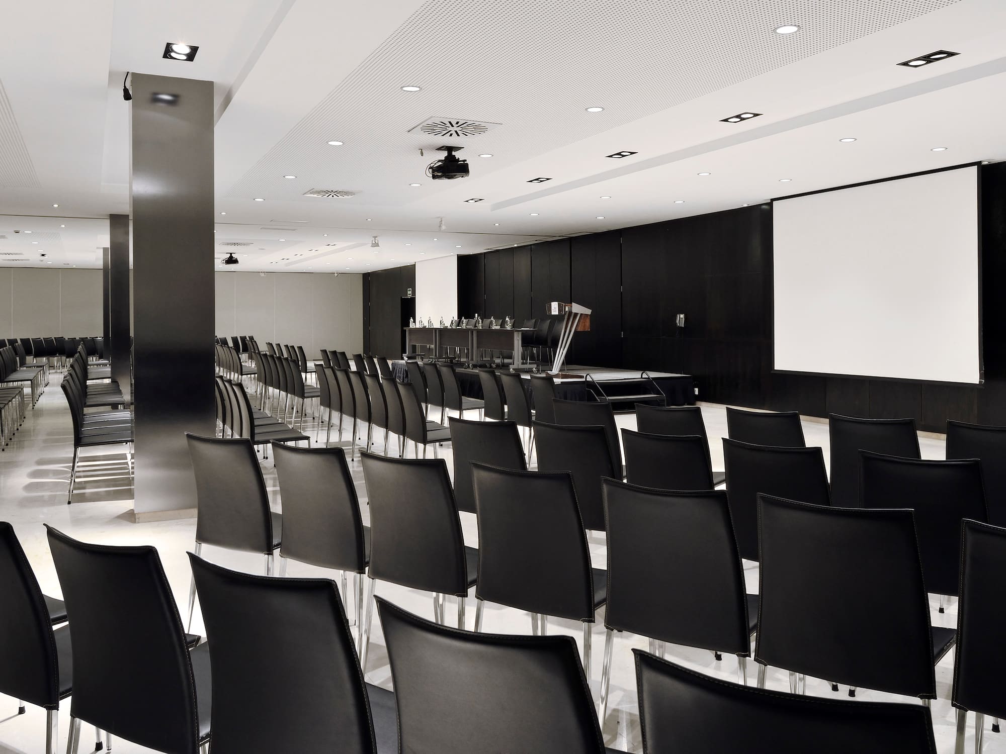 a room with black chairs and a projector screen.