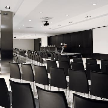 a room with black chairs and a projector screen
