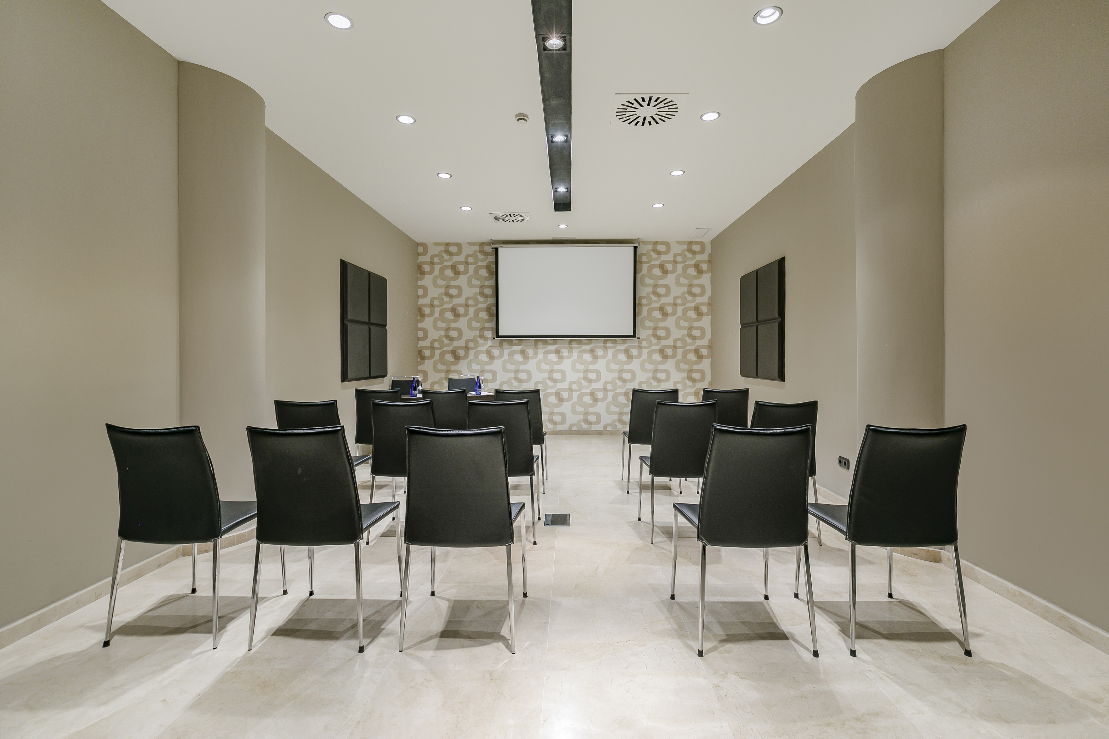 Modern conference room with black chairs, projection screen, and accent wall.