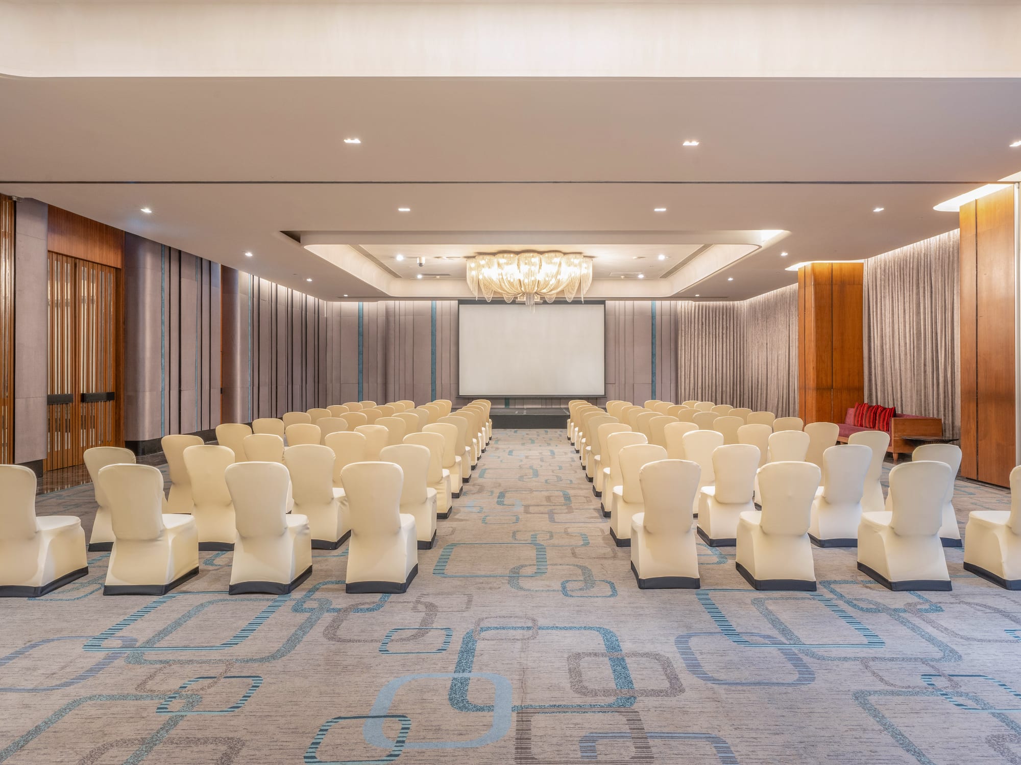 Spacious modern conference room with rows of covered chairs and a projection screen. - The Hotel Bangkok Sukhumvit 26 Affiliated by Meliá, Bangkok